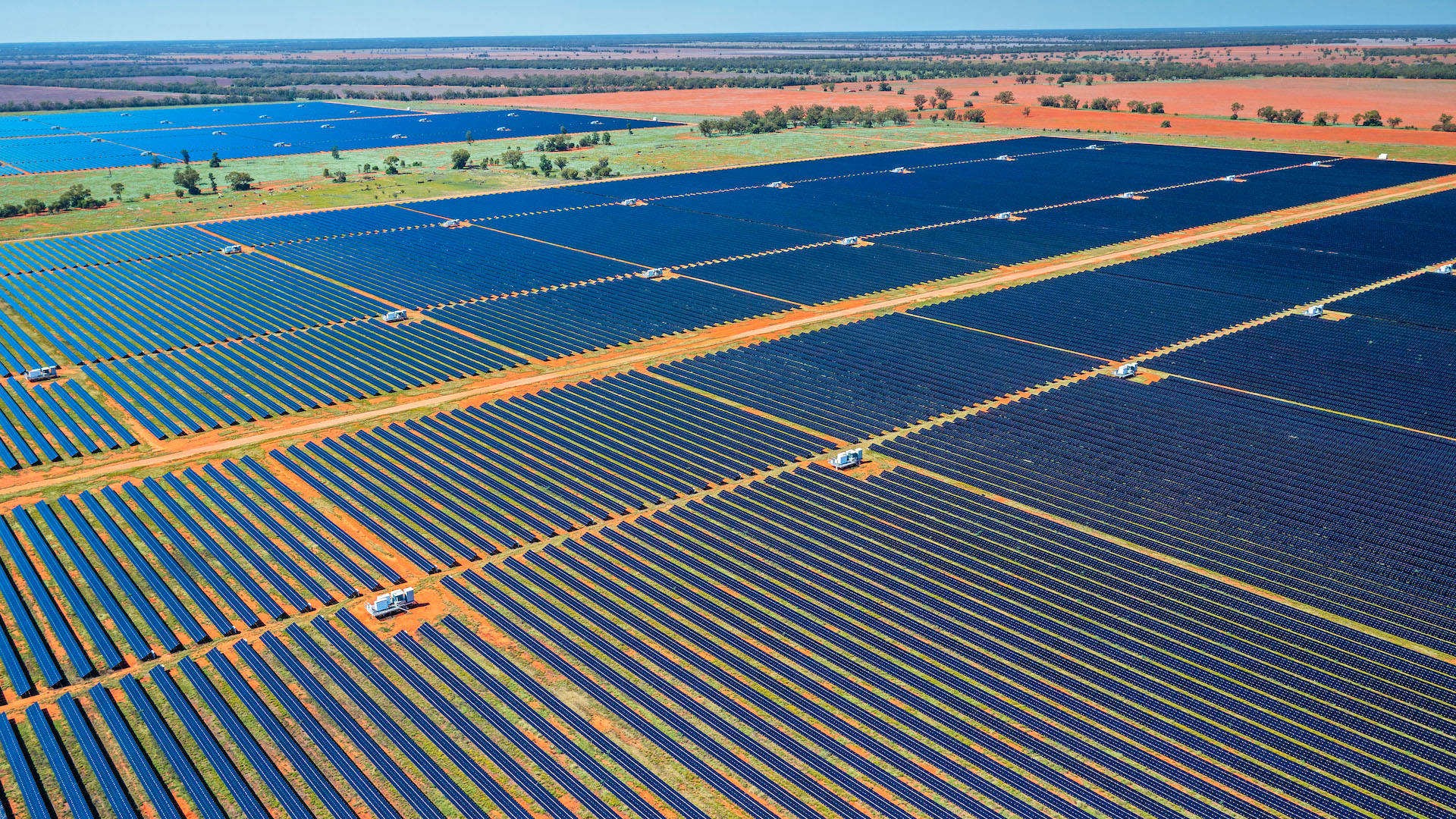 NV Energy光伏發電站 壁紙 — 晴朗藍天下，廣闊太陽能板場地延伸至乾旱紅土的鳥瞰圖。