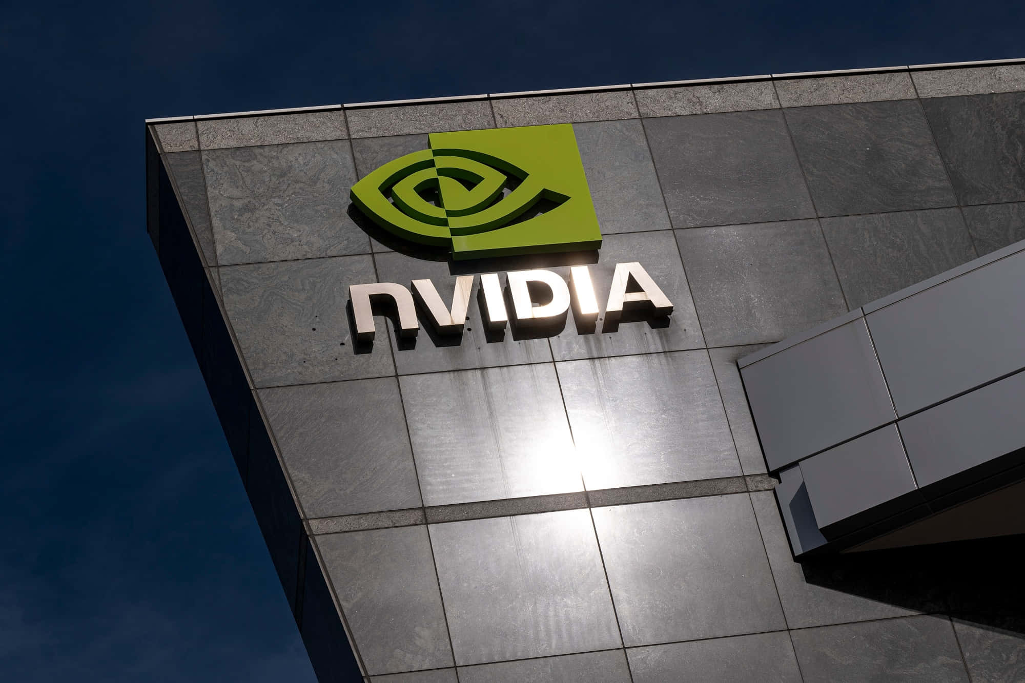 Nvidia 標誌掛在建築物上，襯托藍天 壁紙