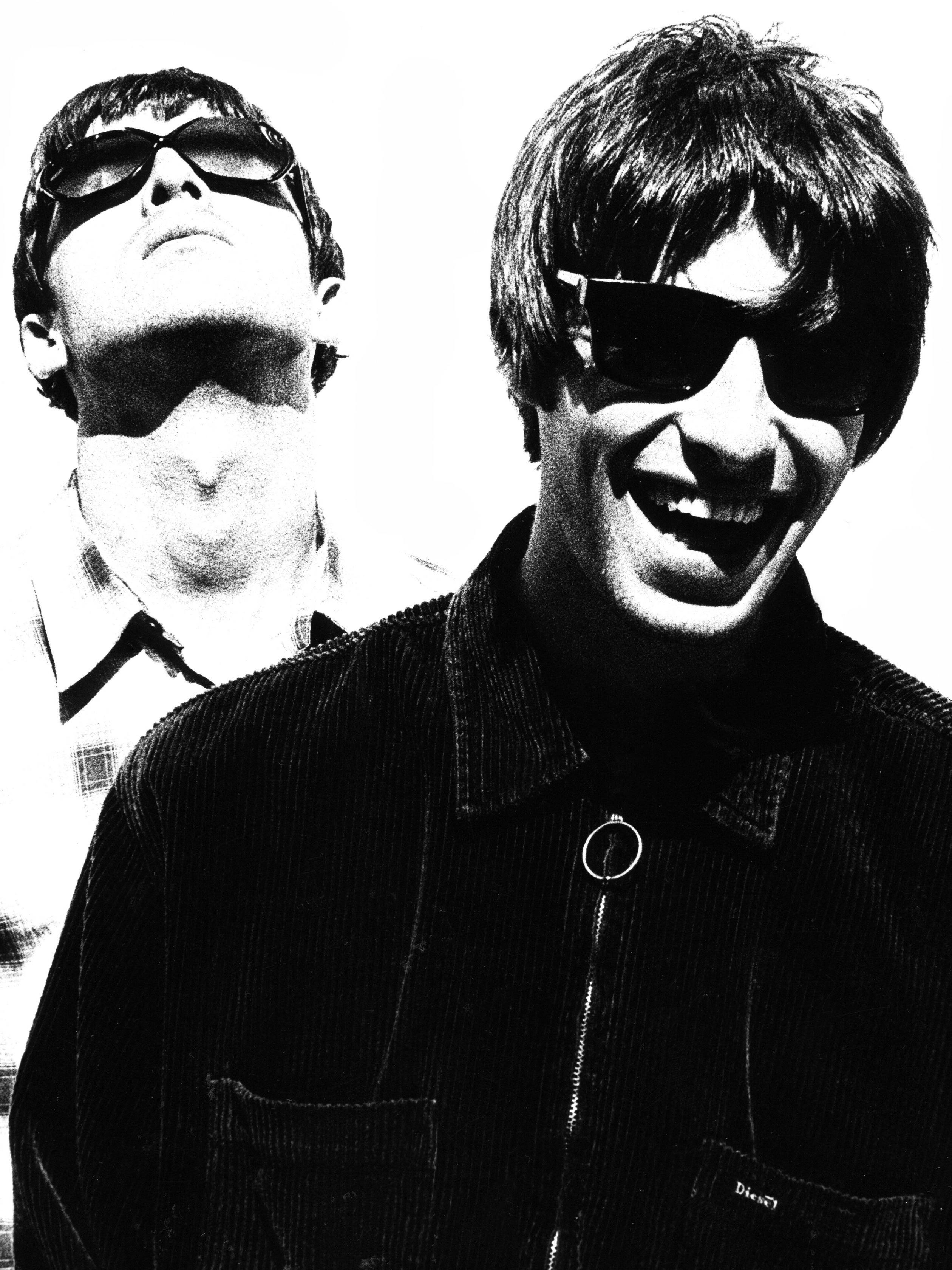 Oasis Liam 與 Noel 壁紙 — 兩個戴住太陽眼鏡嘅男人咧嘴笑，向上望，背景係純白色，高對比黑白效果。