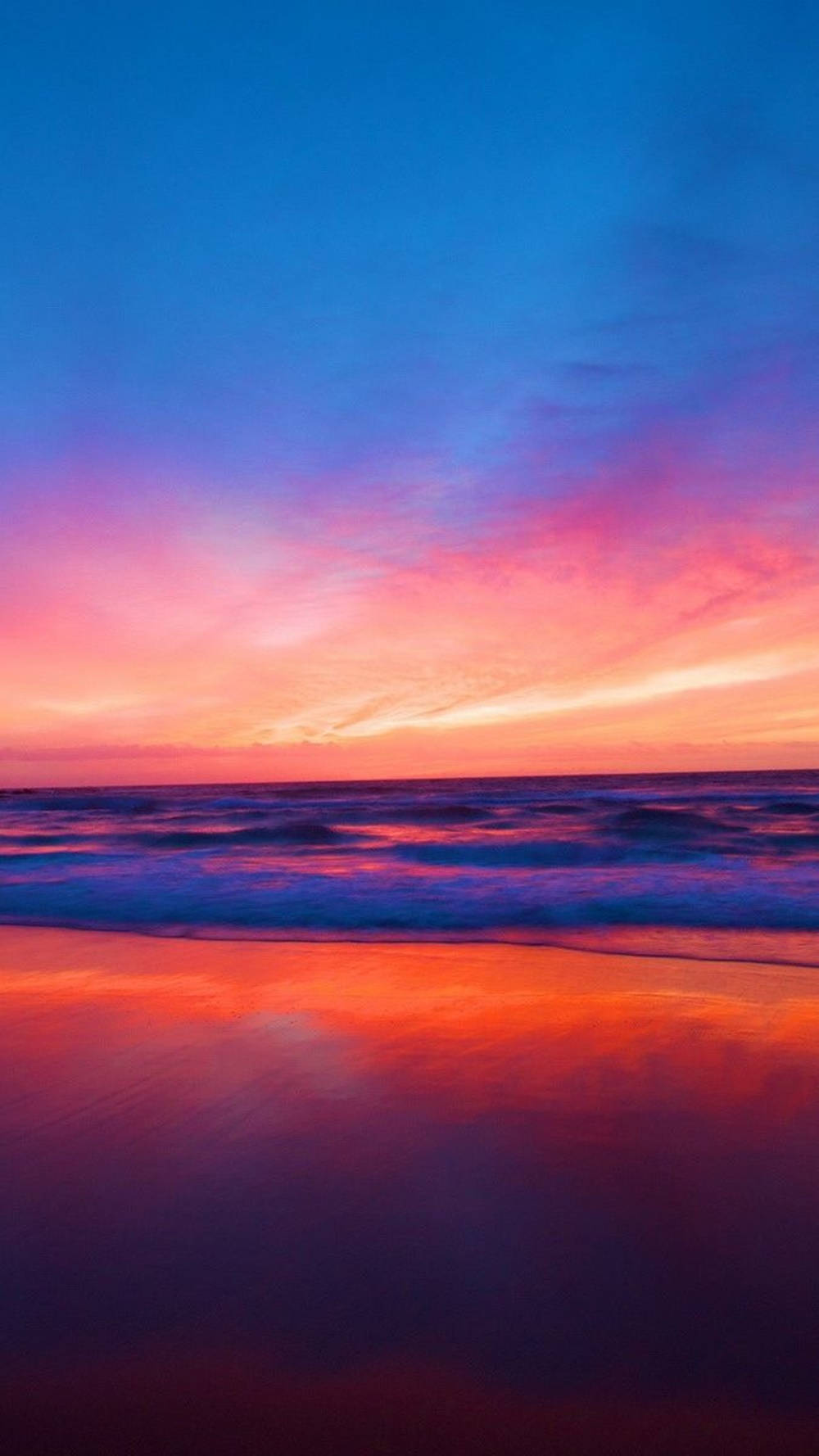 海洋上色彩斑斕的夕陽，多彩的天空倒映在濕沙上。
