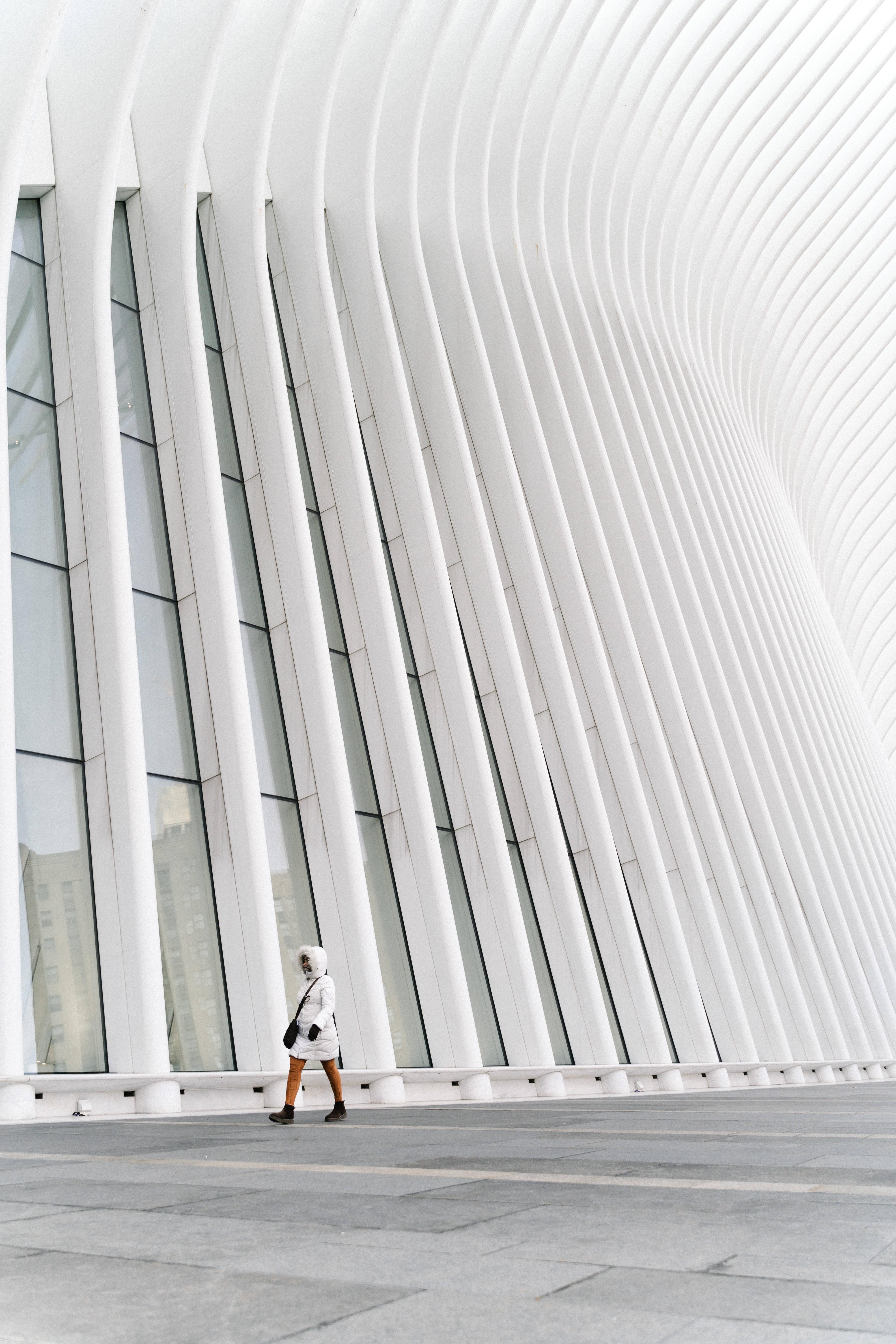 白色簡約 Oculus 建築 壁紙 — 一個孤獨的人走過現代城市建築的白色曲線建築，天空多雲。