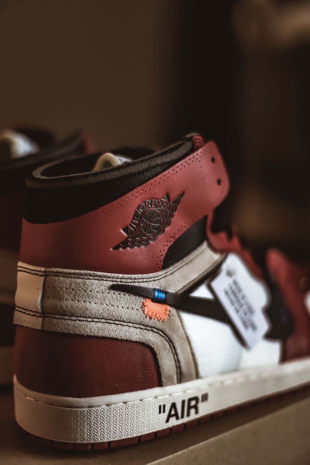 穿著時尚運動風的Off White Jordan 1 壁紙 — 一對紅白黑色Jordan運動鞋的特寫，帶有Off White品牌標誌和藍色標籤。