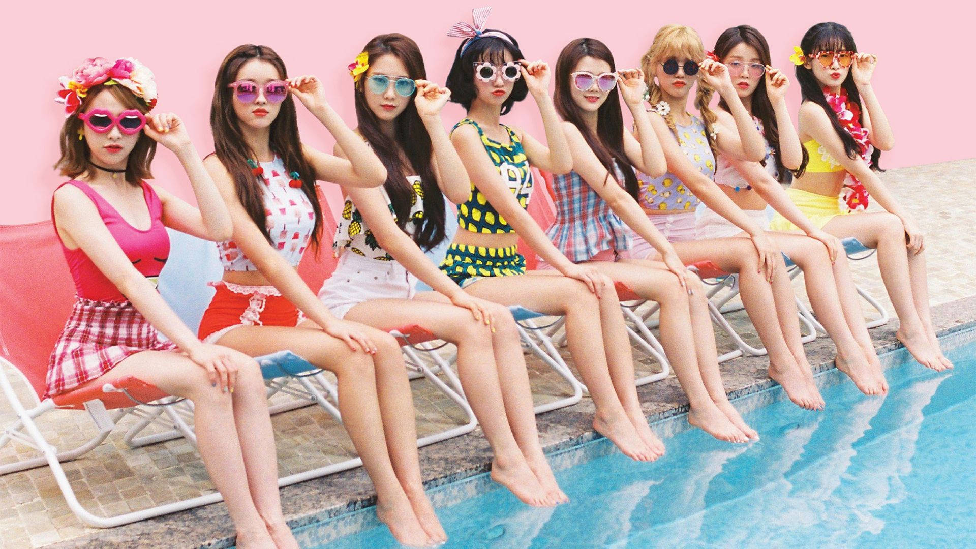 Oh My Girl A-Ing 夏日概念寫真 壁紙 — 七位時尚女性穿著色彩繽紛的泳衣和太陽眼鏡，在粉紅色牆壁旁的泳池邊俏皮地擺姿勢。