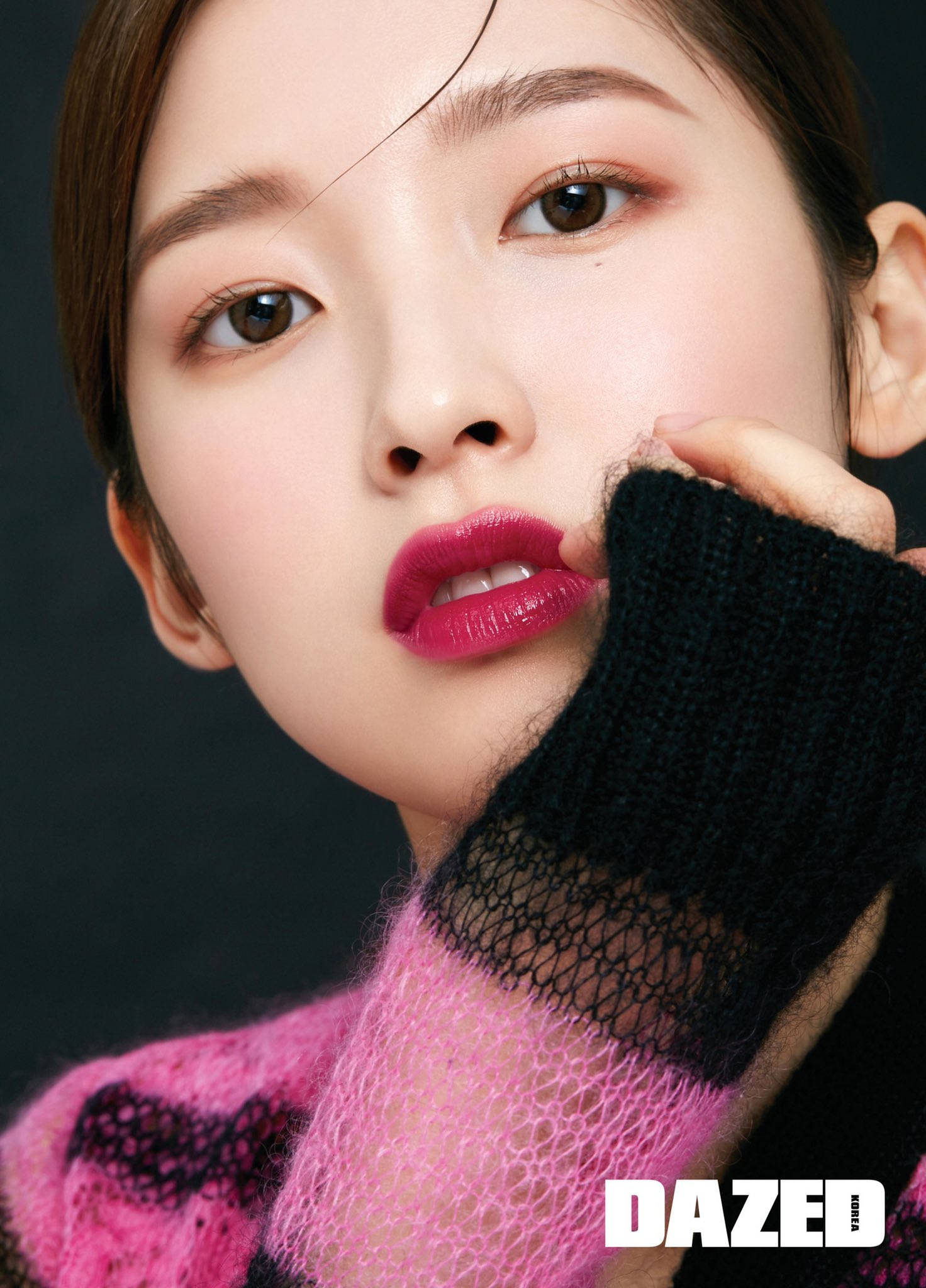 Oh My Girl Arin Dazed 專屬寫真 壁紙 — 一個特寫肖像，一位女性擁有鮮豔的粉紅嘴唇，穿著黑粉相間的網眼毛衣，背景為深色。