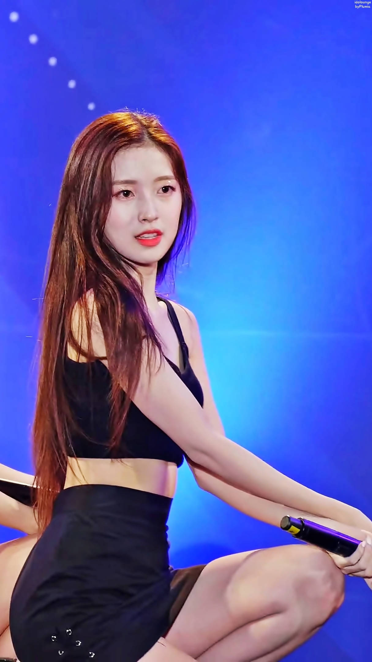 OH MY GIRL Arin 黑色造型 壁紙 — 一位身穿黑色服裝的女性表演者在充滿活力的藍色燈光下蹲在舞台上，手持麥克風。