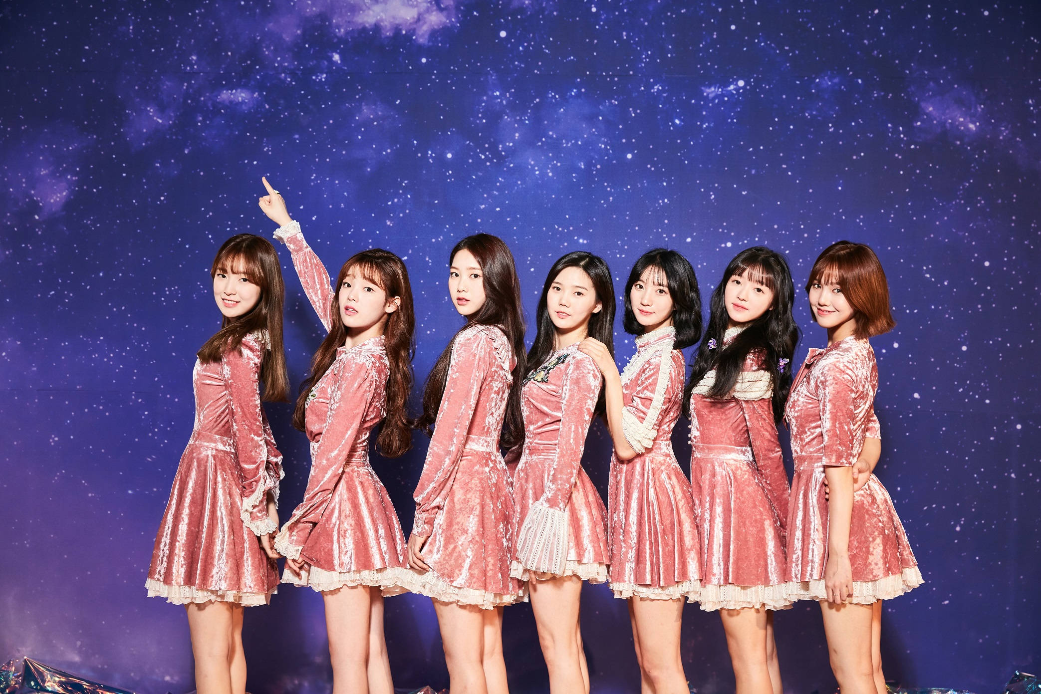 Oh My Girl《The Fifth Season》夢幻造型 壁紙 — 七位年輕女性身穿閃閃發光的粉紅色天鵝絨連衣裙，在宇宙星空背景下擺姿勢，其中一位向上指著。