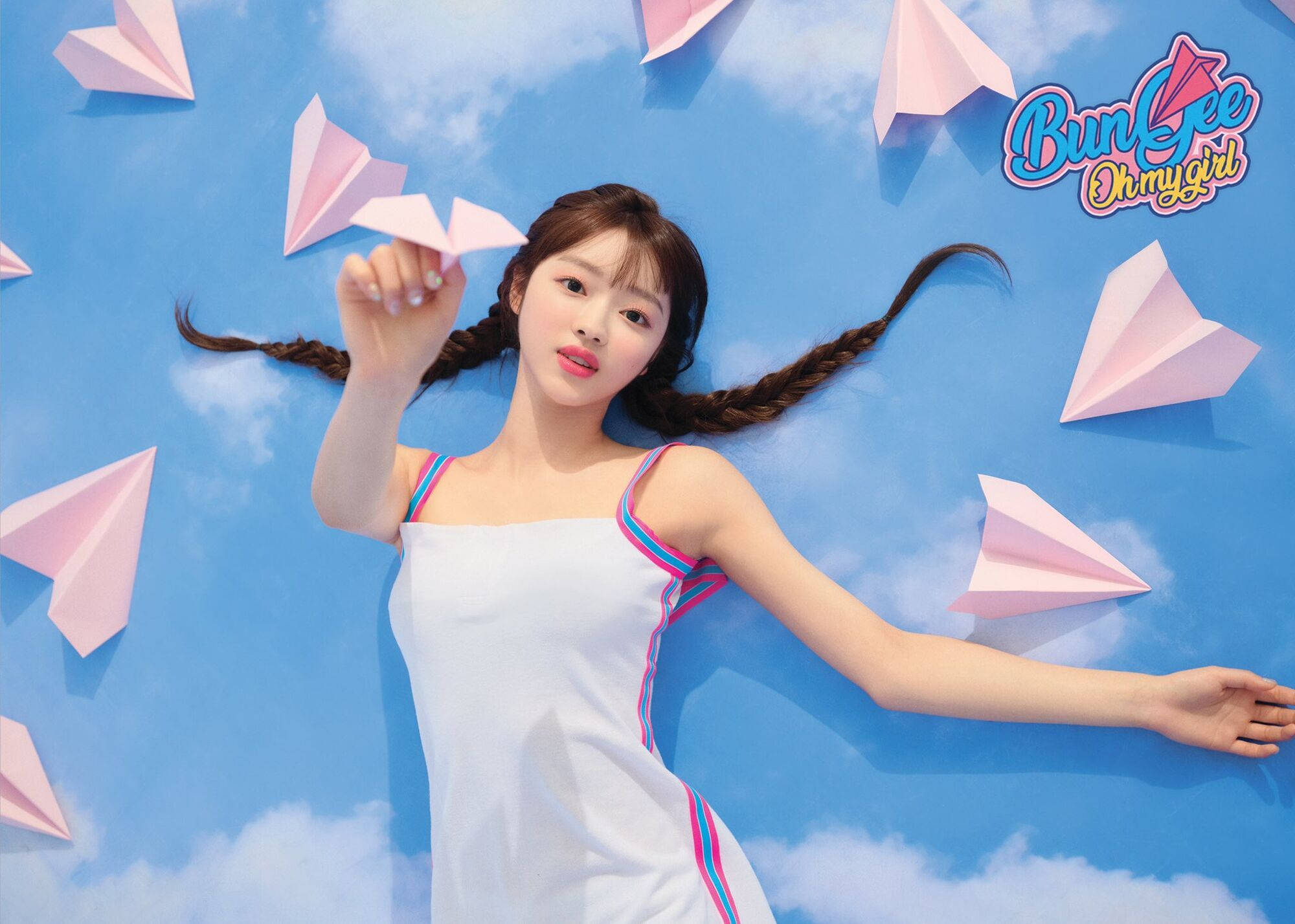 OH MY GIRL YooA《Bungee》歌曲造型 壁紙 — 一位辮子年輕女子躺在藍天背景上，手持粉紅色紙飛機，周圍漂浮著紙飛機。
