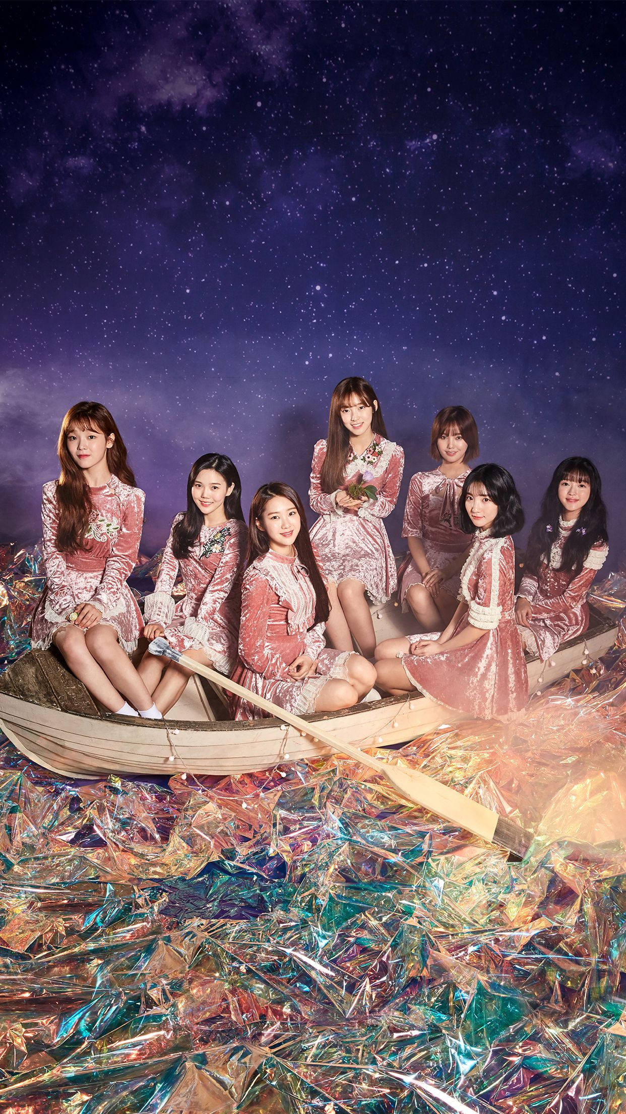 OH MY GIRL 星空氛圍造型 壁紙 — 七位身穿閃亮粉紅色連衣裙的女性坐在一艘木船上，漂浮在閃爍彩虹色箔紙的海洋上，背景是繁星點點的紫色夜空。