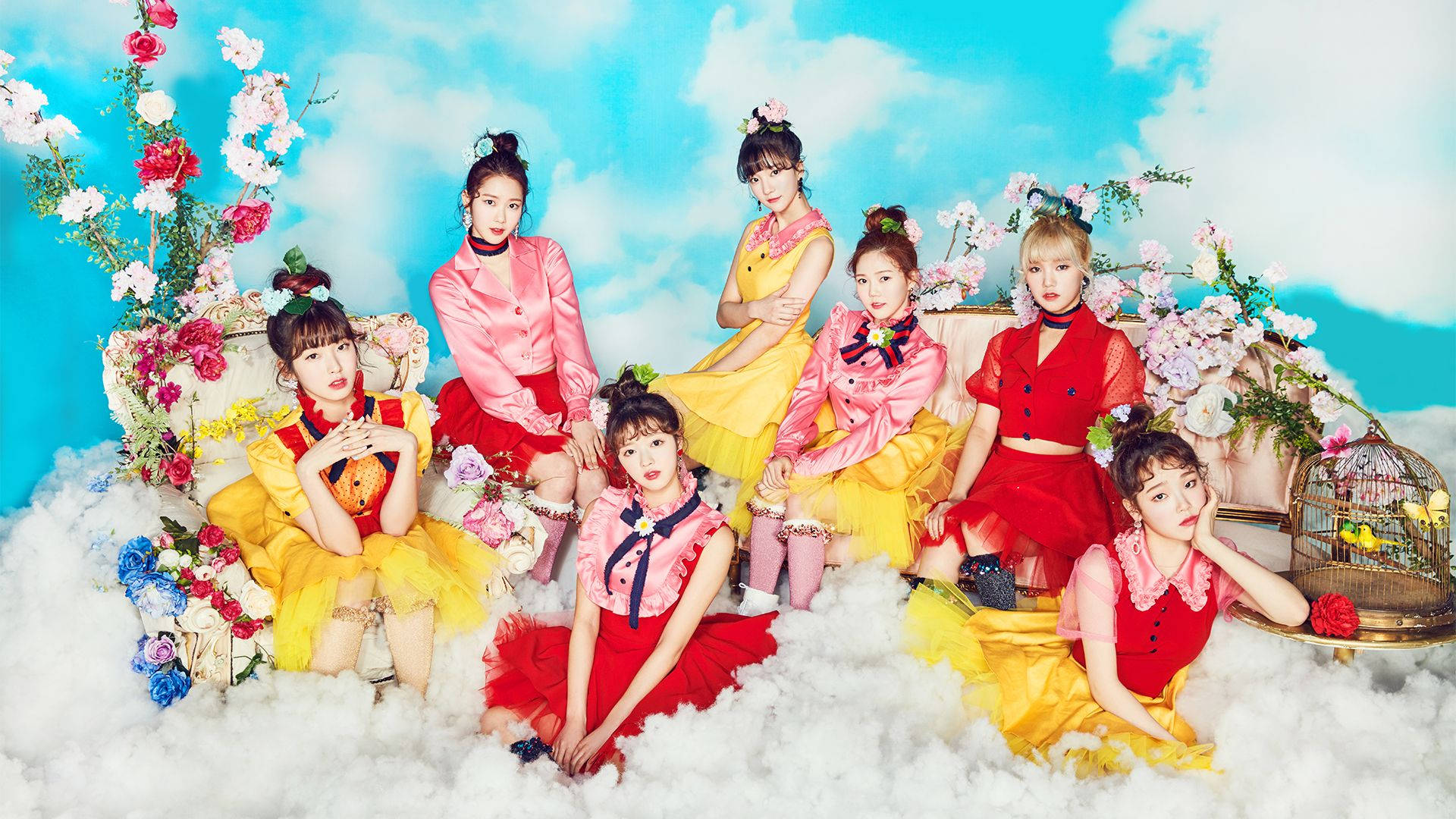 Oh My Girl 服裝東方風 壁紙 — 七位身穿鮮豔紅黃服飾的女性，在蓬鬆雲朵和盛開花朵之間，以明亮的藍天為背景擺出姿勢。