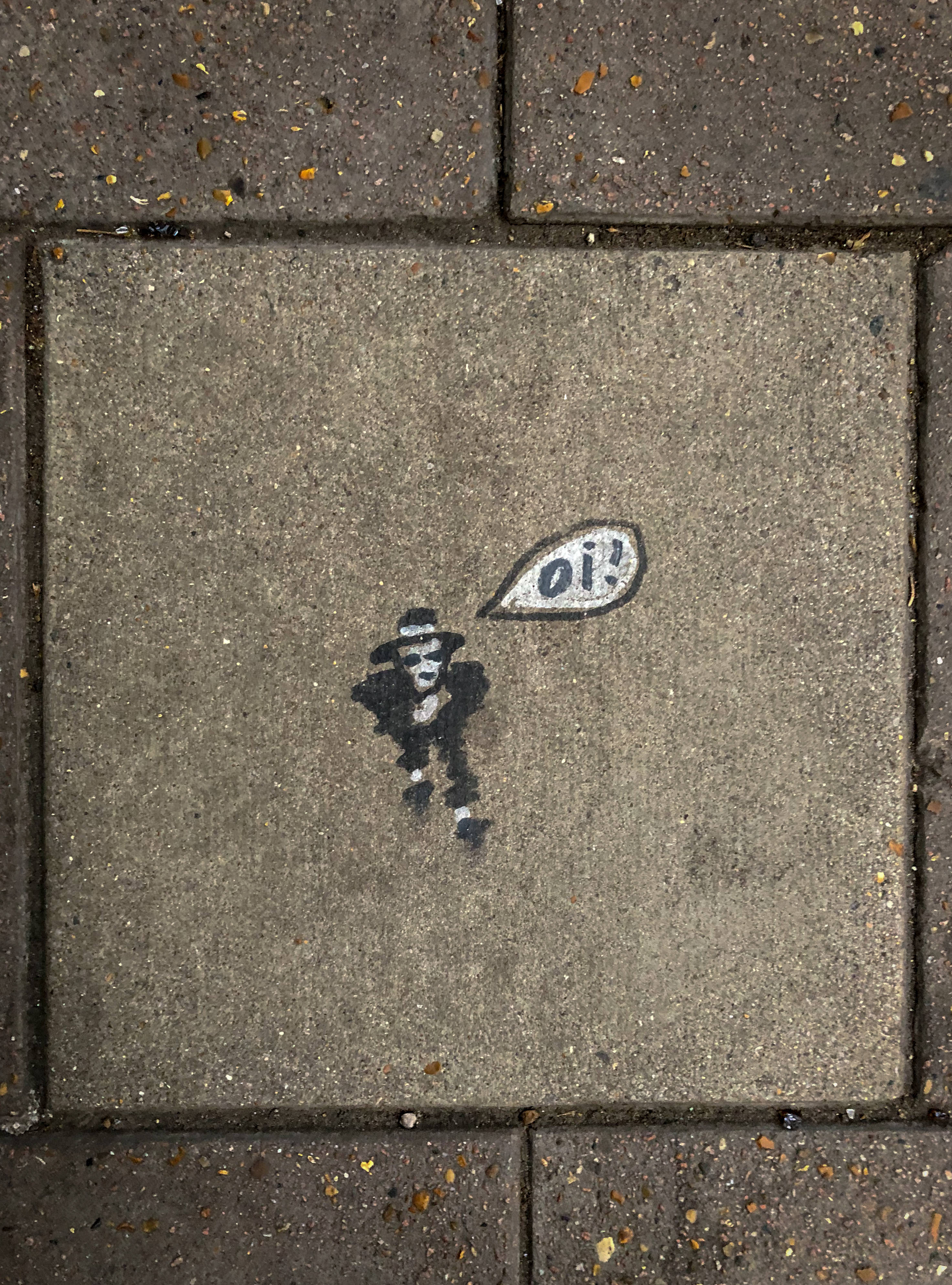 「Oi!」極簡主義街頭藝術 壁紙 — 灰色行人路磚上，一個戴帽的卡通人物用粉筆畫出大叫「Oi！」的圖案。