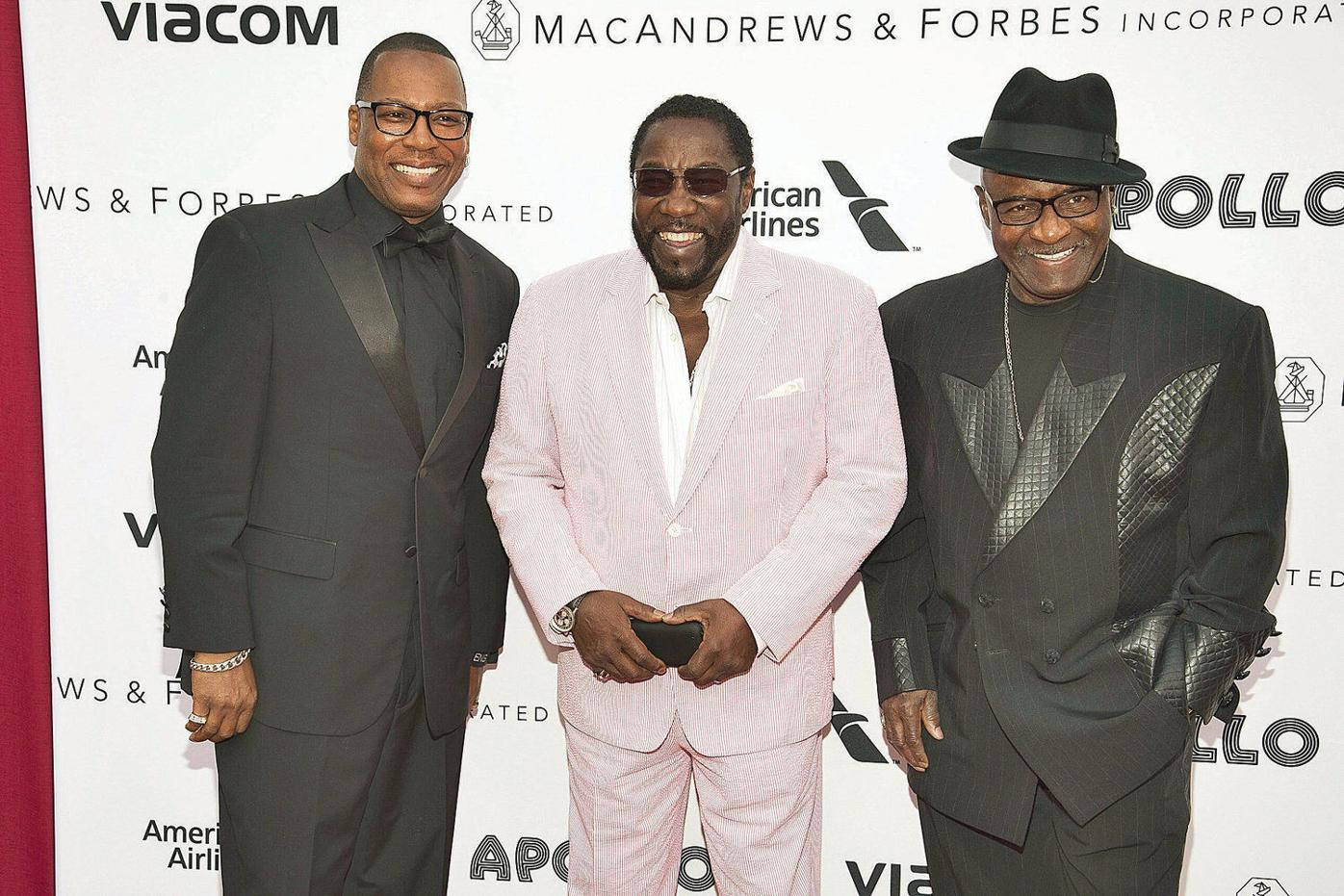 Ojays 九月經典合照 壁紙 — 三位微笑的黑人男士穿著時尚西裝，在品牌背景前自信地擺姿勢參加企業活動。
