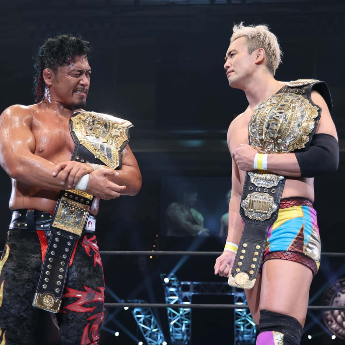 兩名摔角手在擂台上對峙，手持冠軍腰帶。