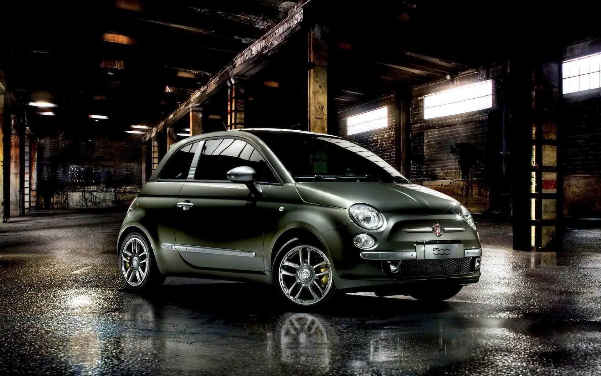 Fiat 500l 桌布 壁紙 — 一輛時尚的橄欖綠色菲亞特500停泊在光線昏暗的工業倉庫中，地面濕滑反光。