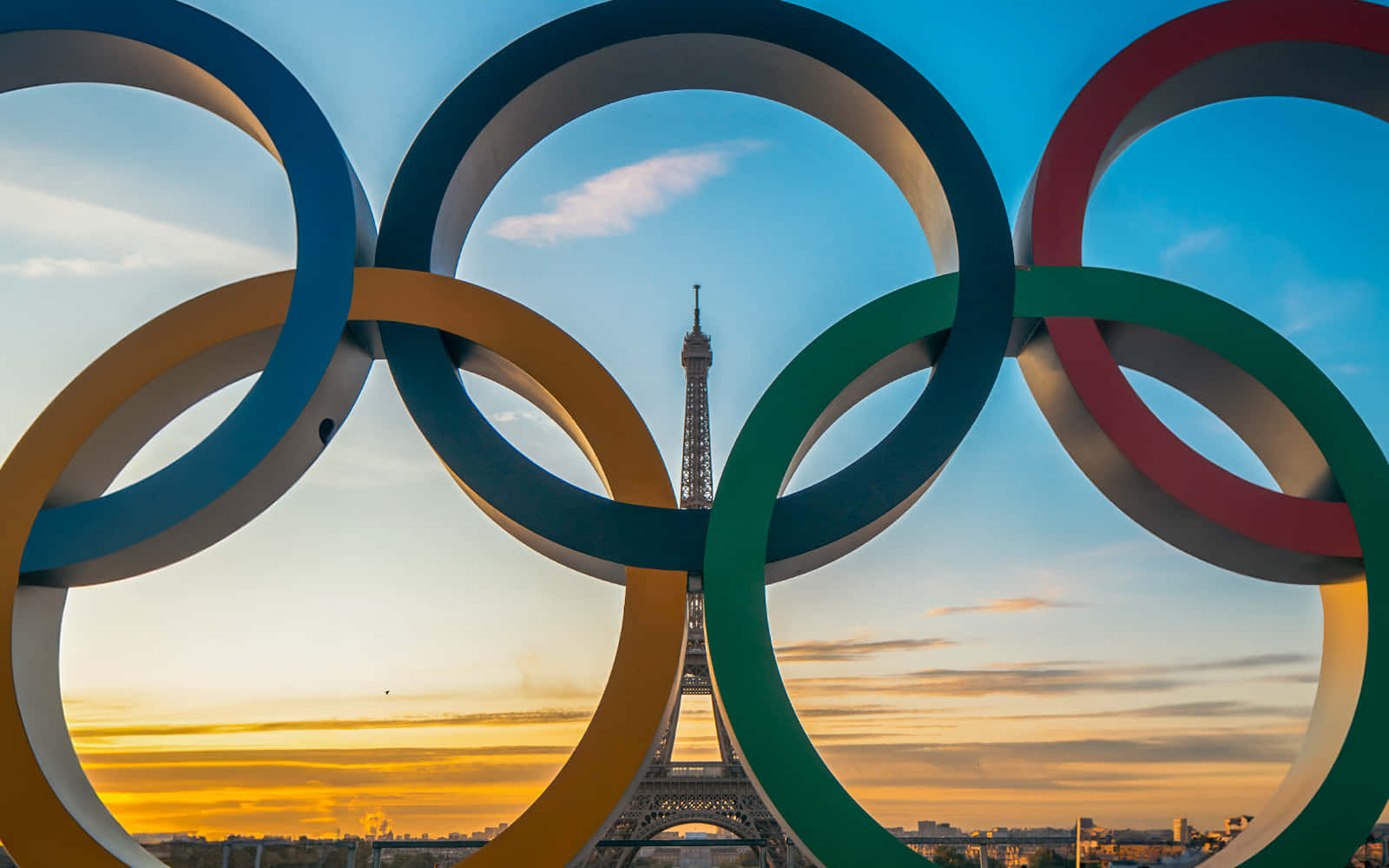  壁紙 — 奧運五環框住艾菲爾鐵塔，背景係金色日落天空。
