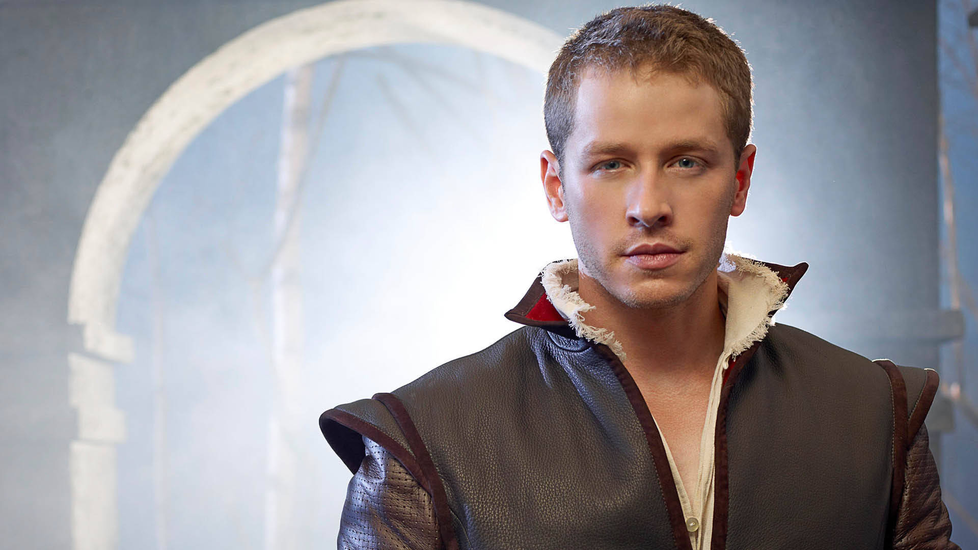 《Once Upon A Time》喬什·達拉斯 壁紙 — 一個穿著棕色皮背心、毛領的男人站在一個霧氣瀰漫的石拱門前，環境昏暗。