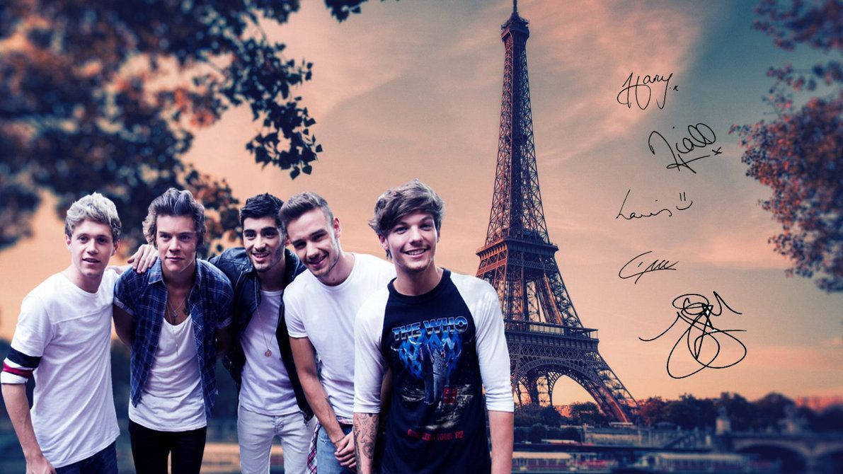 One Direction 在巴黎埃菲爾鐵塔 壁紙 — 五個微笑的年輕男子在溫暖的日落時分於艾菲爾鐵塔前擺姿勢，右側有手寫簽名。