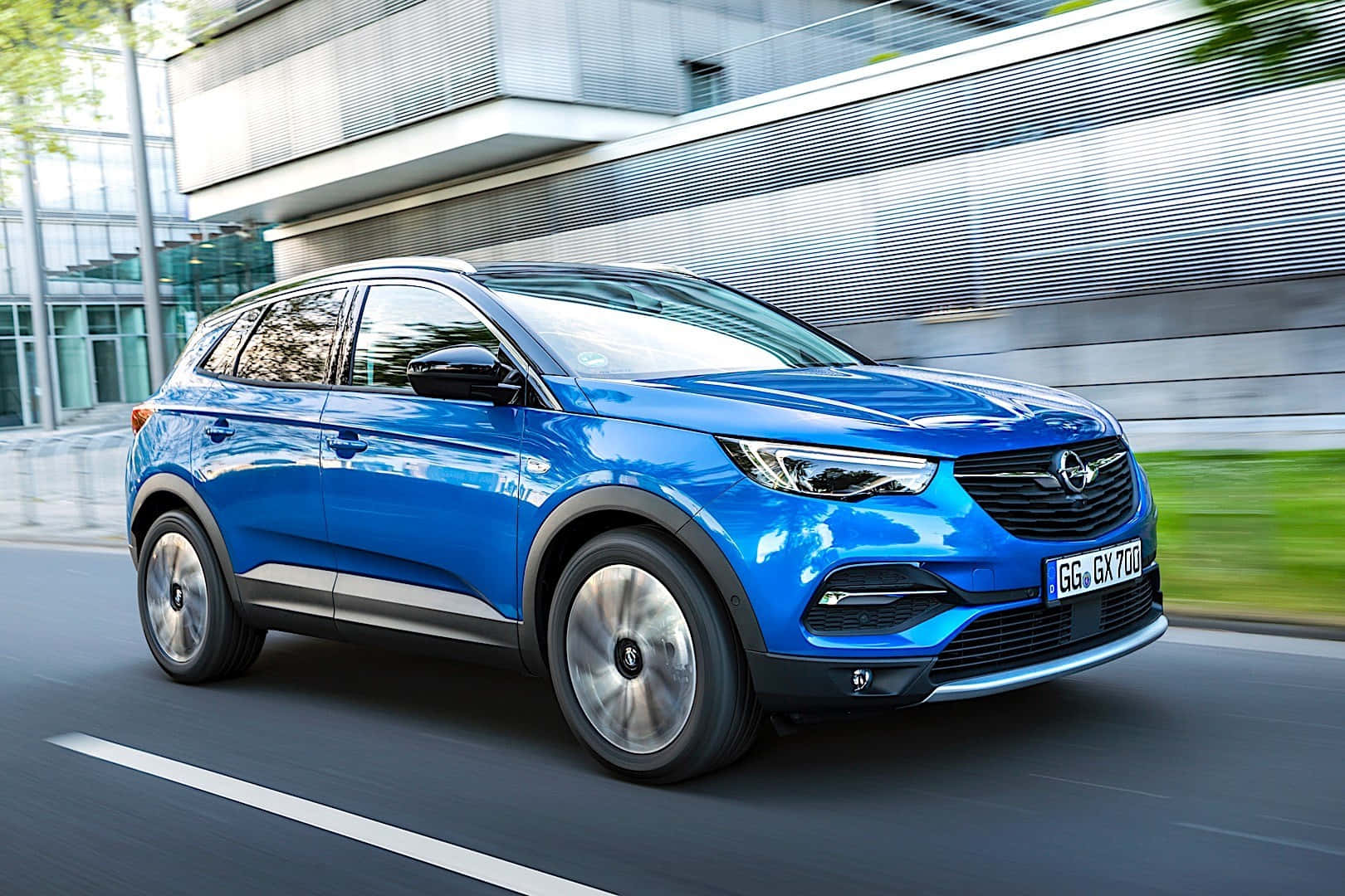 Opel Grandland X 桌布 壁紙 — 一輛充滿活力的藍色歐寶跨界SUV在現代城市街道上疾馳，背景帶有動態模糊效果。