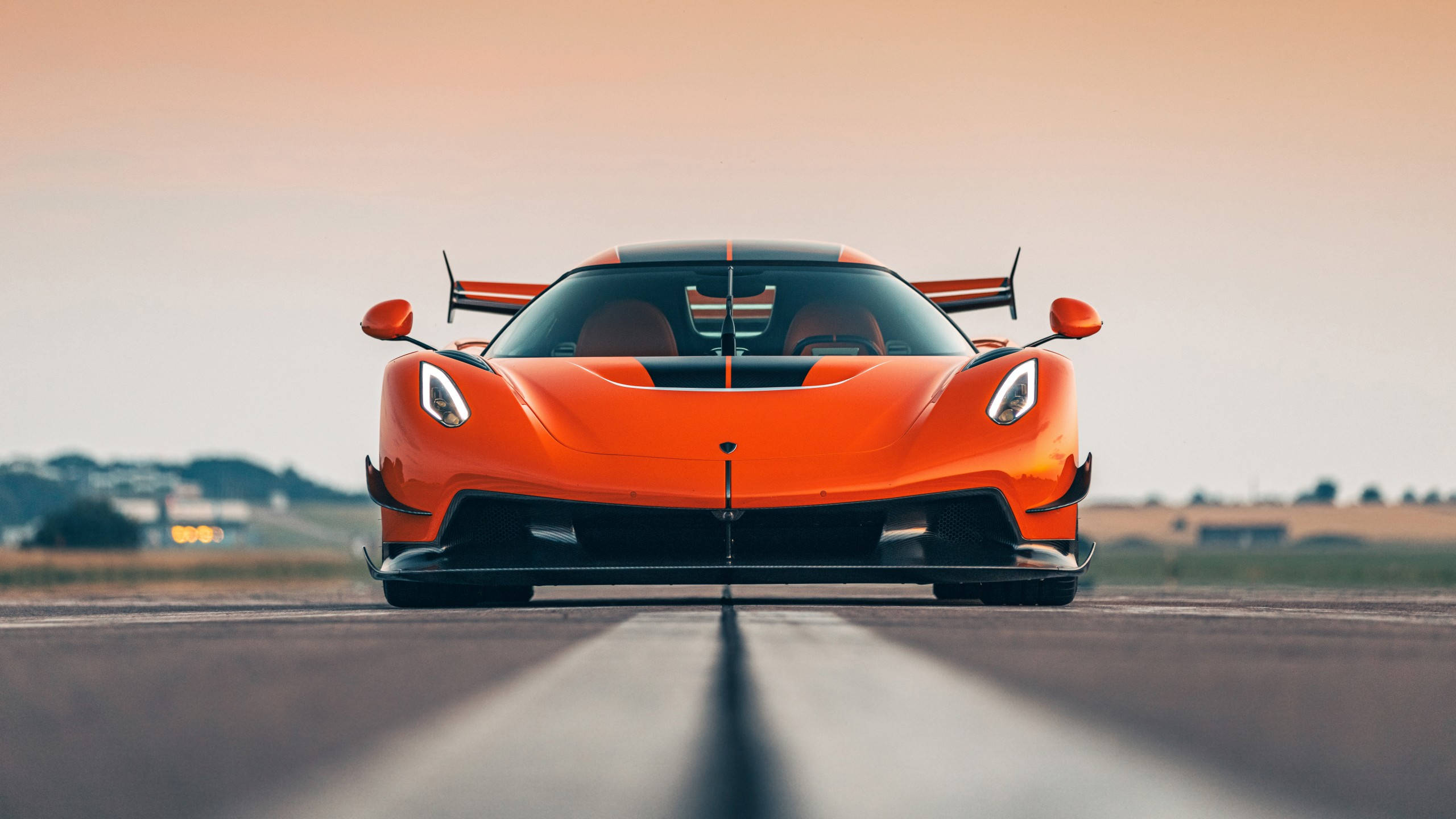 橙色 Koenigsegg 超跑在日落時分的跑道上