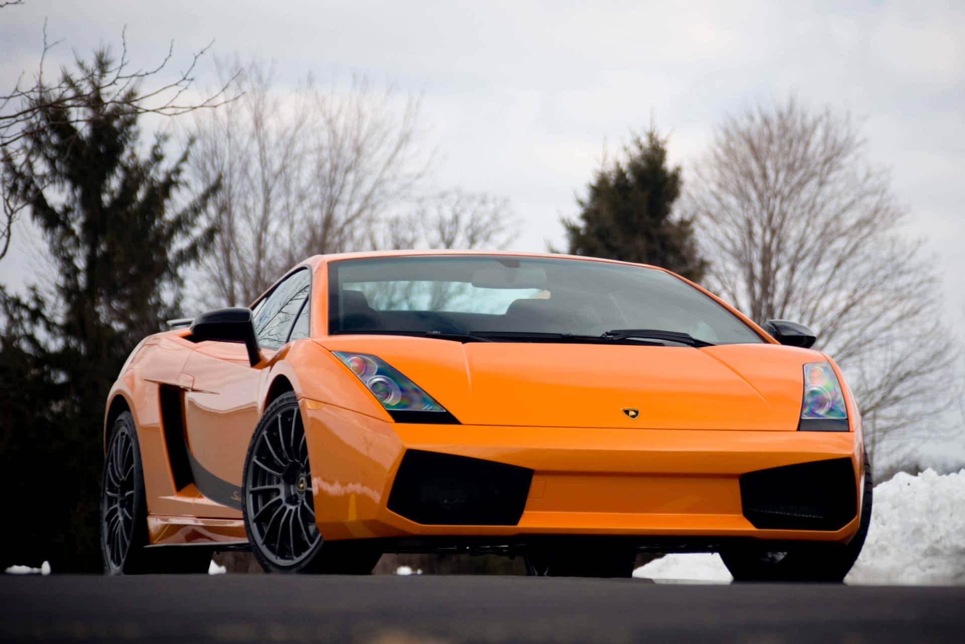 Lamborghini Gallardo 桌布 壁紙 — 一輛鮮橙色林寶堅尼Gallardo跑車停泊在雪路上，背景有光禿禿的樹木。