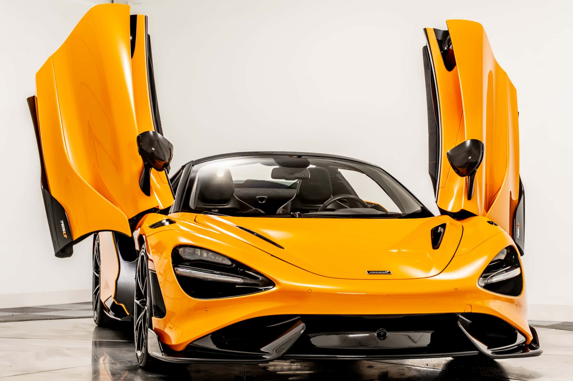 Mclaren 765lt 桌布 壁紙 — 一輛充滿活力的橙色McLaren跑車，鷗翼門打開，在簡約的白色工作室背景下展示其時尚的空氣動力學設計。