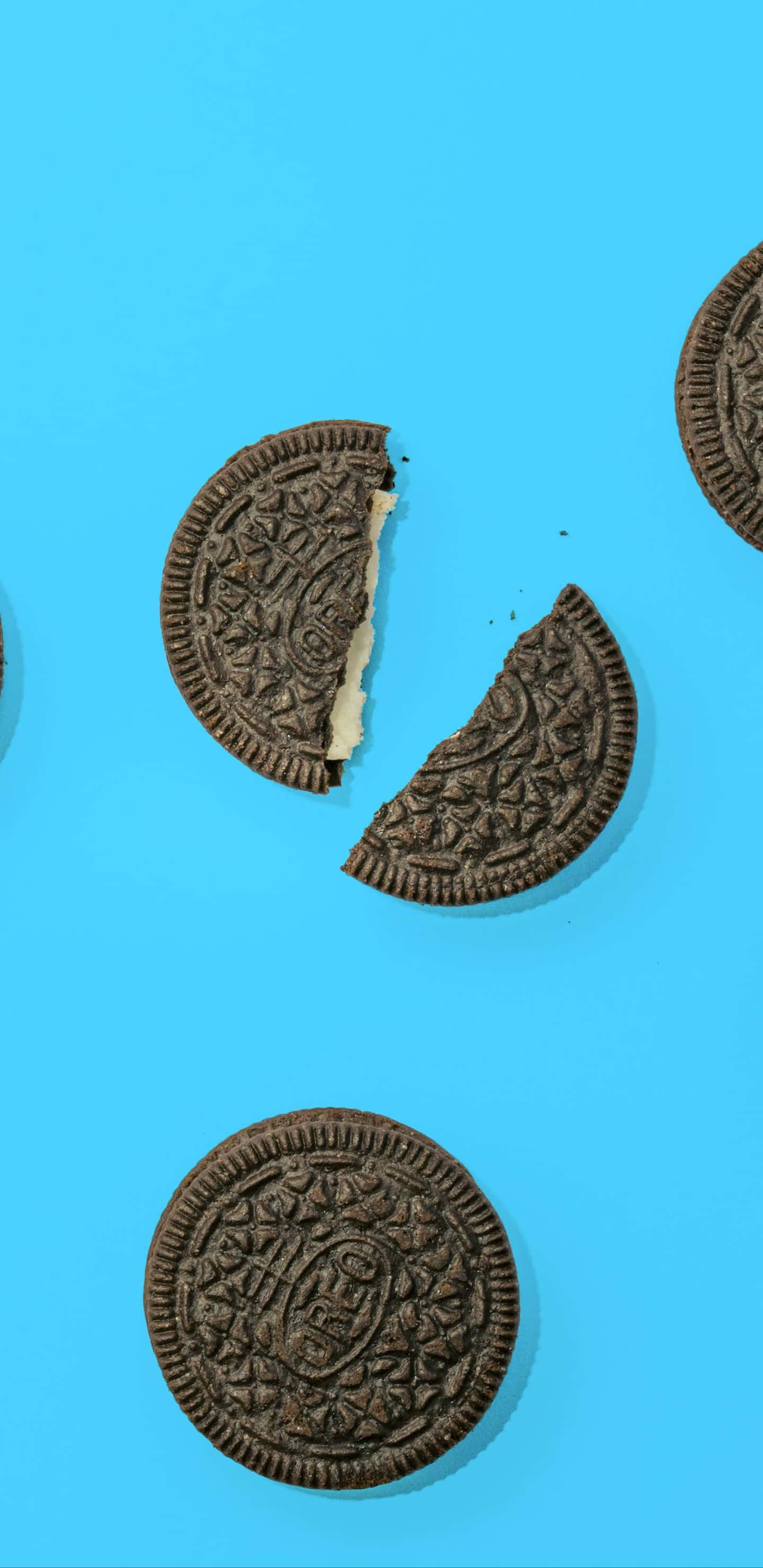 Oreo 風格像素 3XL 曲奇餅乾背景 壁紙 — 碎裂的Oreo曲奇餅乾帶有奶油夾心，散落在明亮的藍色背景上。