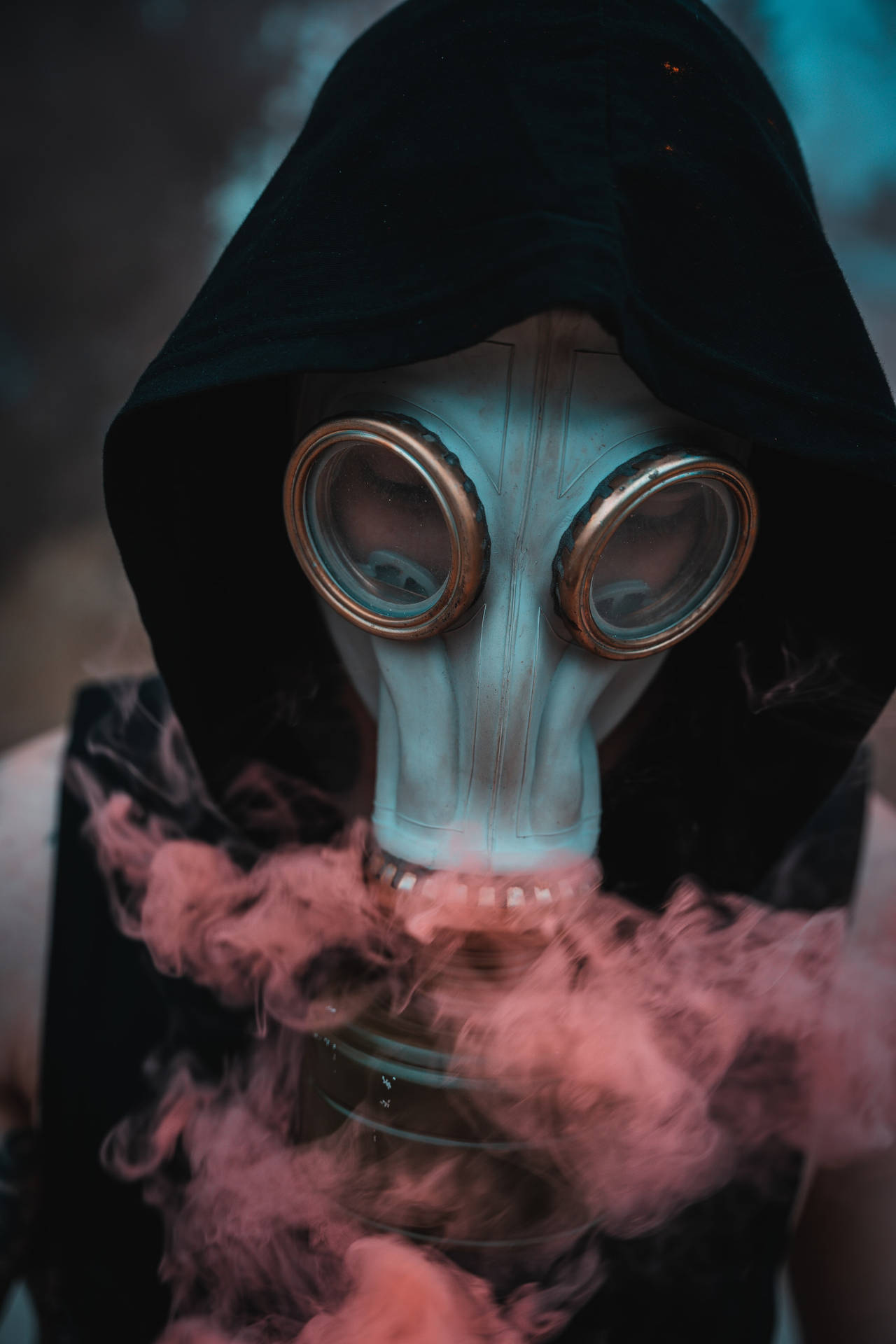 身穿黑色連帽衫的人戴著防毒面具呼出粉紅色煙霧。