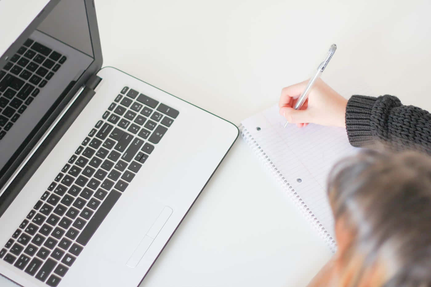 溫習 桌布 壁紙 — Overhead view of a person writing in a notebook beside an open laptop on a clean white desk.
