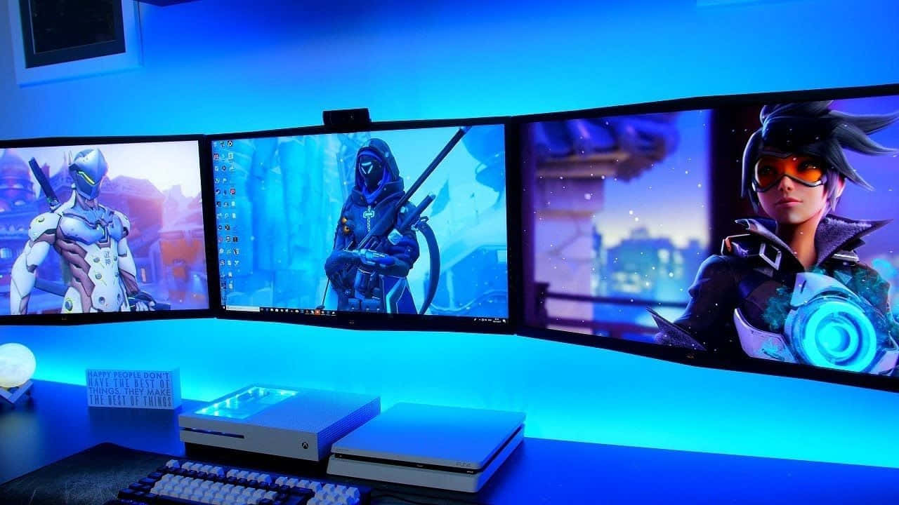 《Overwatch 2》遊戲設置圖片 壁紙 — 三個曲面顯示器在酷藍色環境燈光下，於遊戲桌上顯示充滿活力的Overwatch角色。