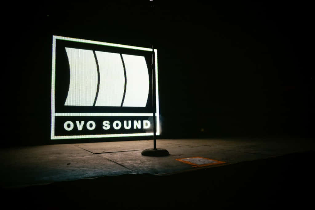 在黑暗的工作室環境中，一個明亮照明的 OVO SOUND 標誌。