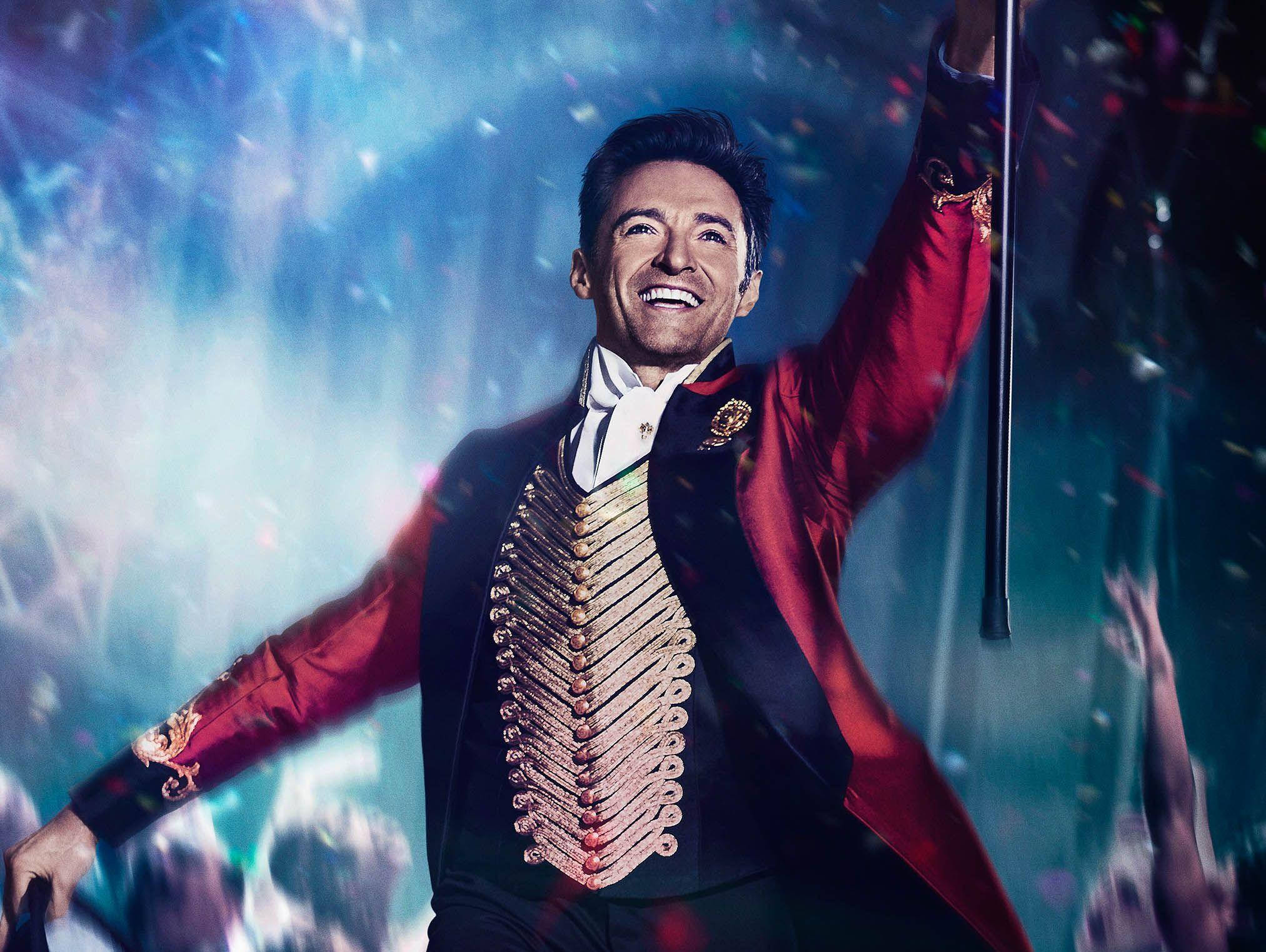 P.T. 巴納姆在《 Greatest Showman 》 壁紙 — 一位身穿紅金色戲服的快樂表演者在璀璨的舞台表演中，在五彩紙屑飄落時露出燦爛的笑容。