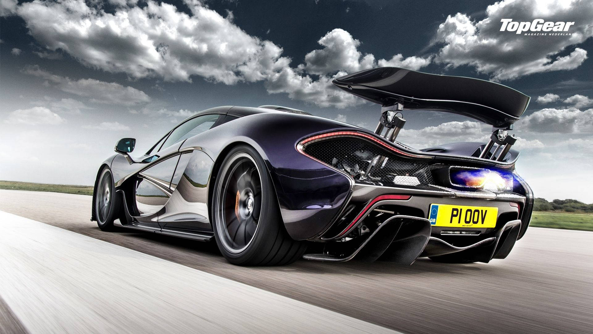 麥拉倫 P1 TopGear 壁紙 — 一架型格黑色McLaren P1超級跑車在戲劇性的多雲天空下於跑道上高速飛馳，尾翼升起。