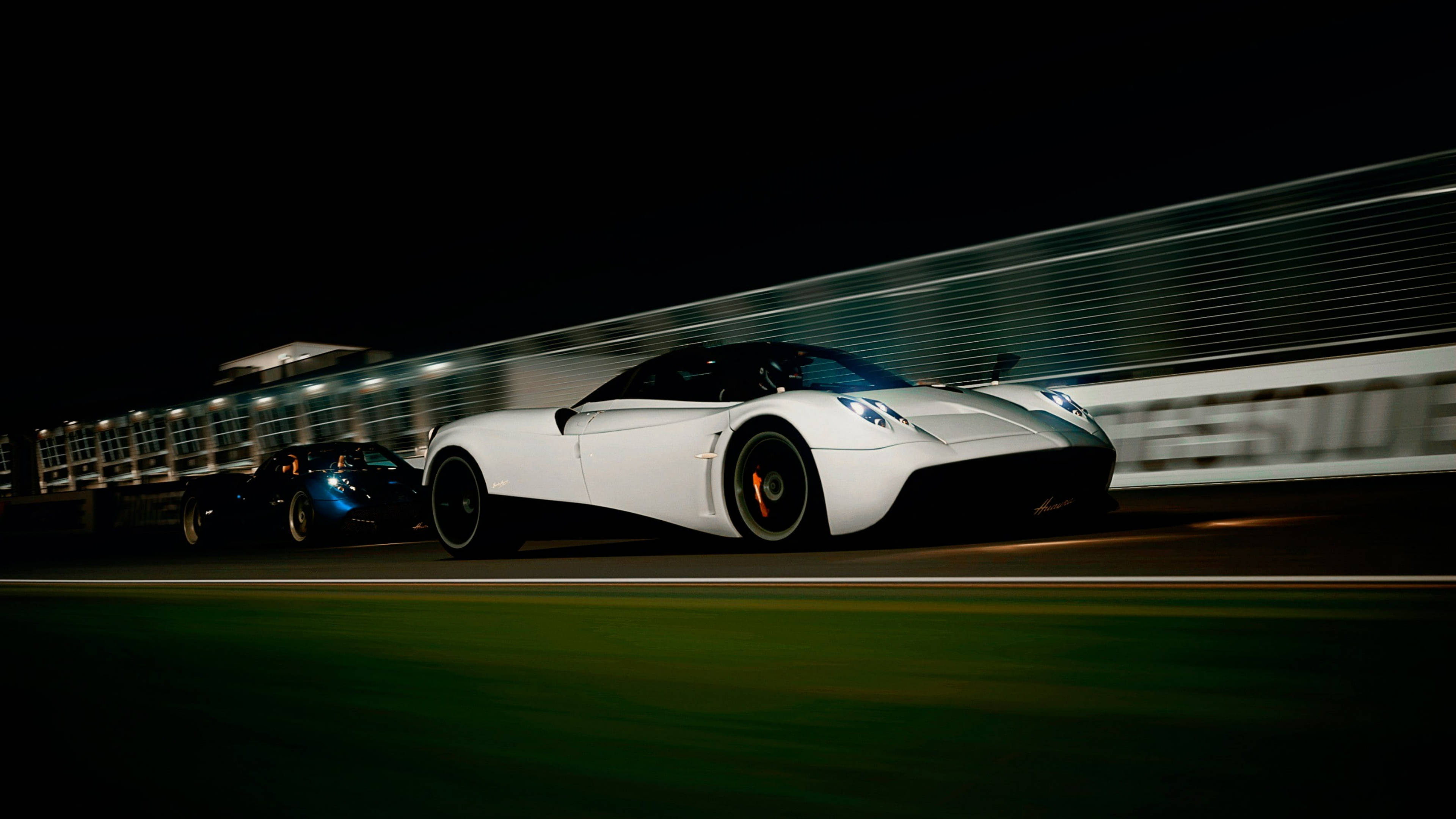 Pagani Huayra 賽道競速 壁紙 — 一輛白色超跑在夜間賽道上疾馳，帶有動態模糊效果。