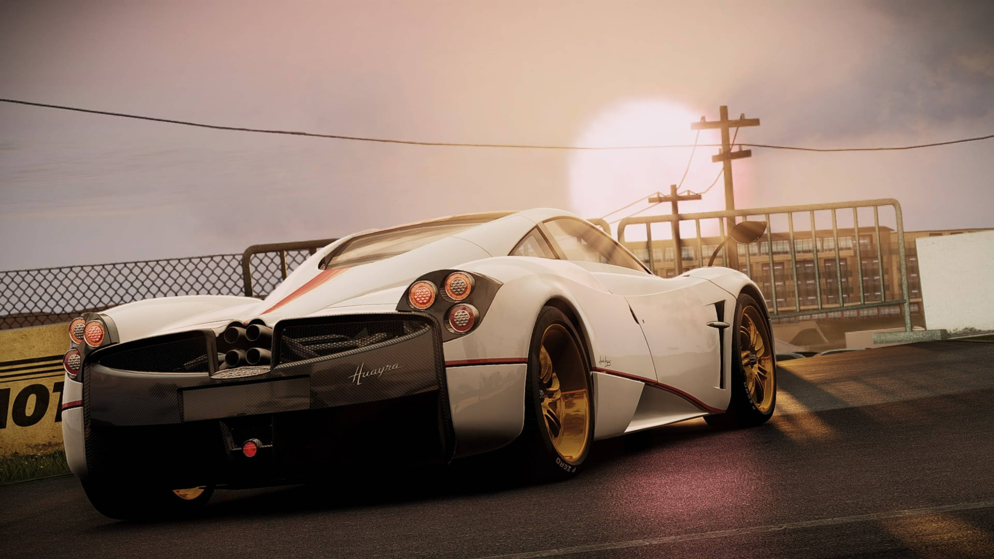 Pagani Huayra 朝曦美景 壁紙 — 一輛白色Pagani Huayra跑車配金色輪圈，在日落時分停泊在賽道上，周圍有溫暖發光的燈光。