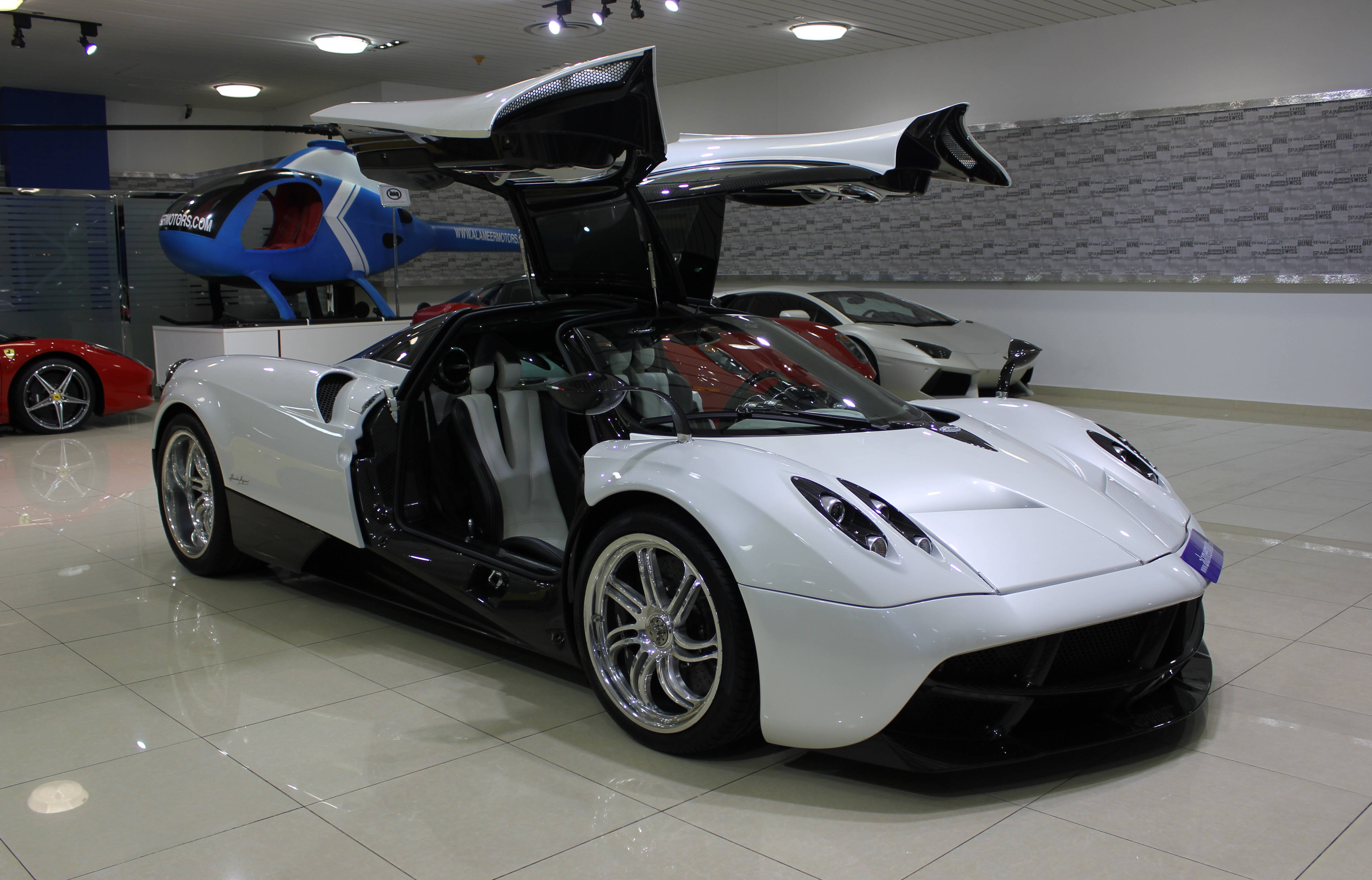 Pagani Huayra 白色限定版 壁紙 — 一輛純白色的帕加尼Huayra打開鷗翼車門，在時尚的豪華車展廳中展示其奢華內飾。