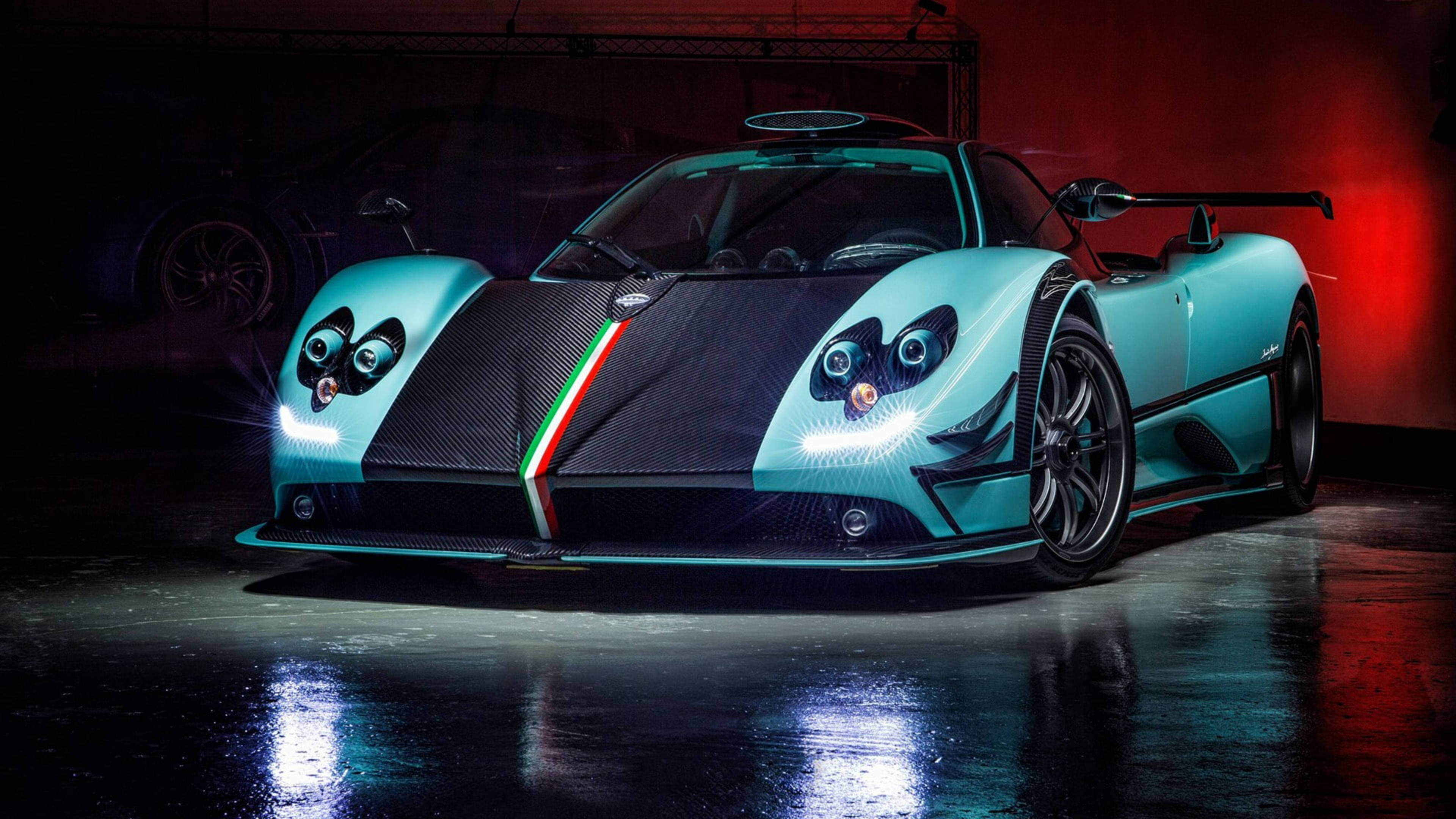 Pagani Zonda 760 RSJX 水藍黑 壁紙 — 一輛帶有意大利國旗裝飾的時尚青綠色帕加尼風神在光亮的車庫中，在戲劇性的紅藍燈光下閃耀。