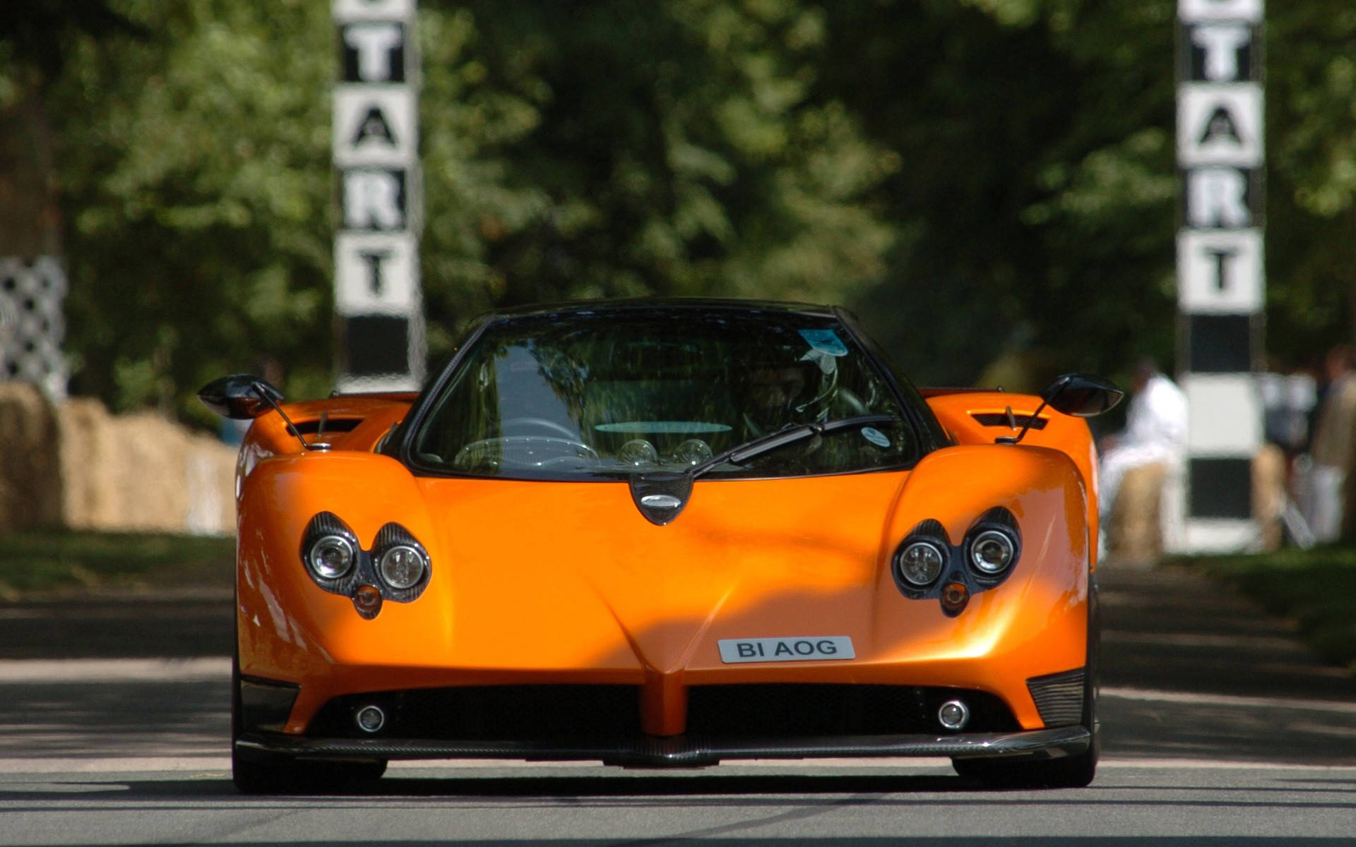Pagani Zonda Roadster F 橙色款 壁紙 — 一輛充滿活力的橙色Pagani Zonda跑車在賽道上向前行駛，道路兩旁有「START」標誌。
