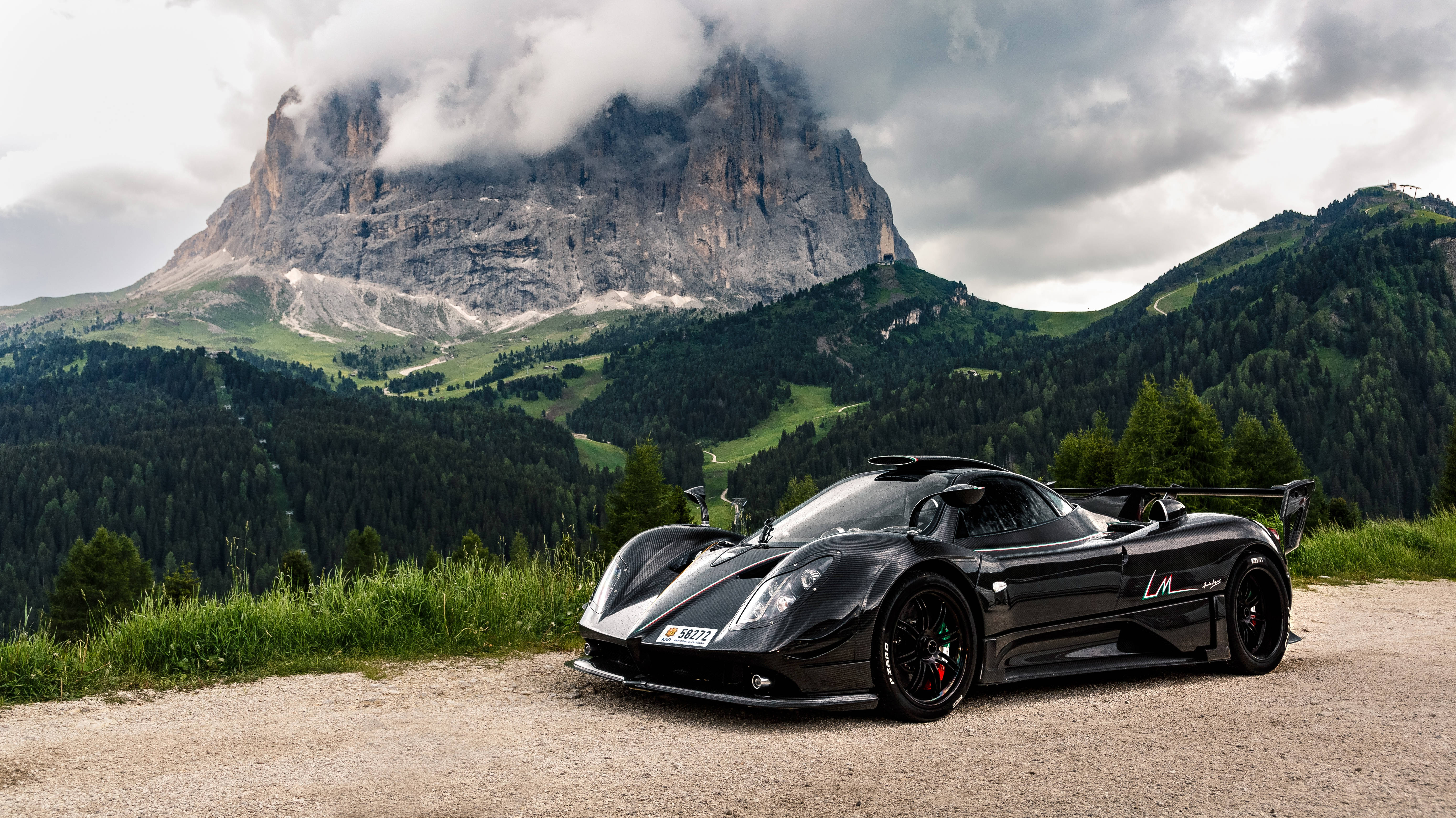 Pagani Zonda 站於加德納山口 壁紙 — 一架時尚的黑色跑車停在碎石觀景點上，背後有戲劇性的山峰在陰天中升起。