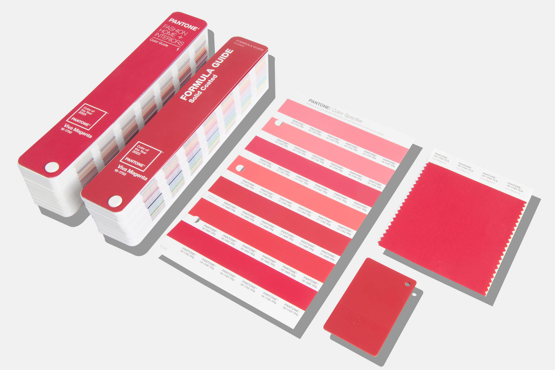 Pantone Viva Magenta 色調板 壁紙 — Pantone 色票書和指南攤開，在潔白的表面上展示鮮豔的紅色和粉紅色。