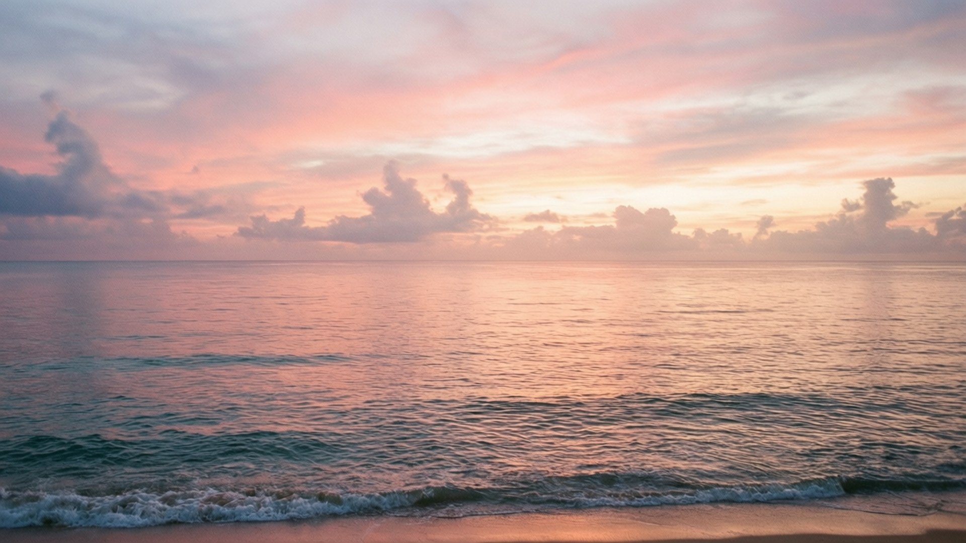 海浪輕輕拍打沙灘，粉橙色夕陽天空下散佈著雲朵