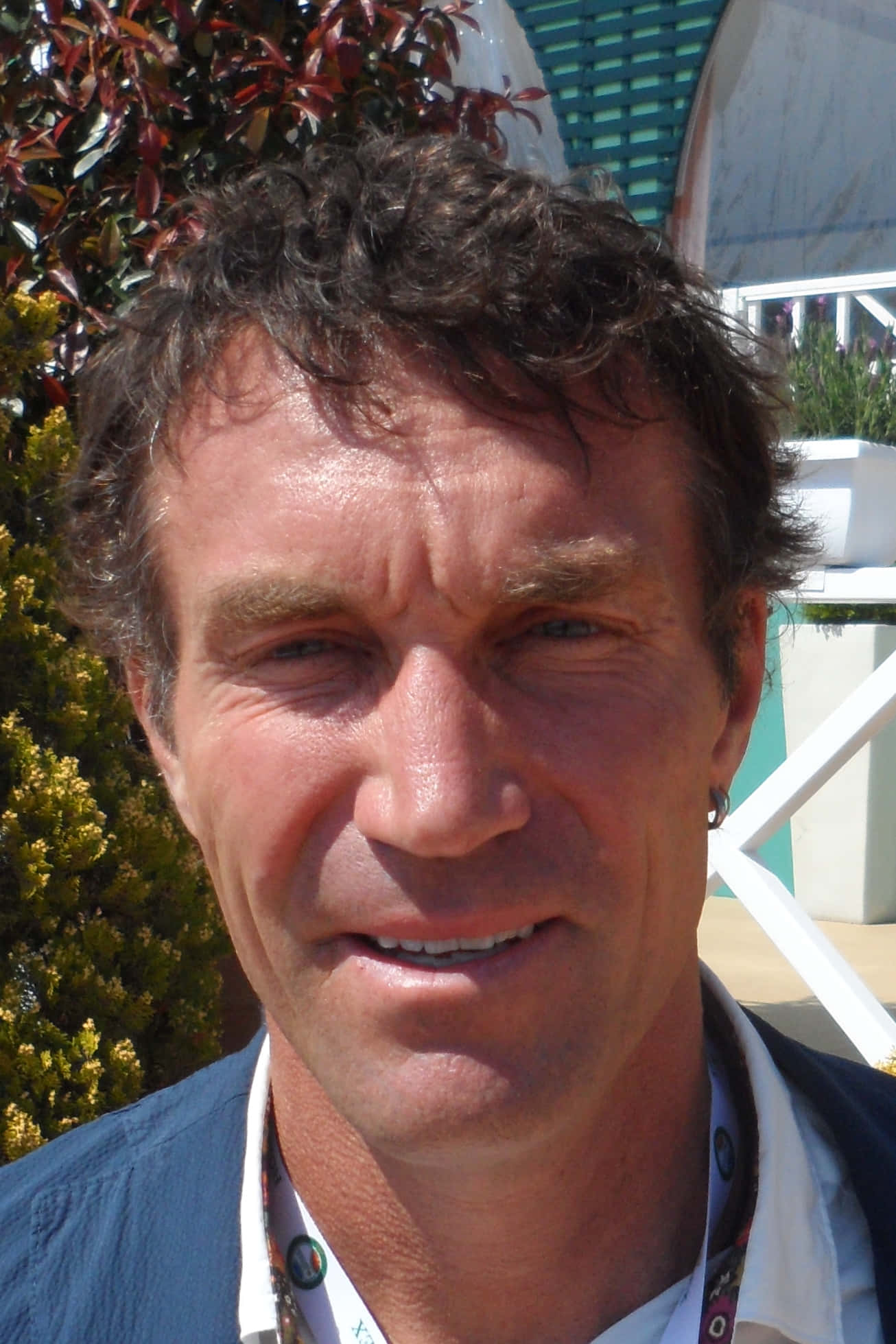 Pat Cash 的自拍時光 壁紙 — 一個微笑男子的特寫肖像，他有捲曲的棕色頭髮和藍色眼睛，在戶外明亮的陽光下。