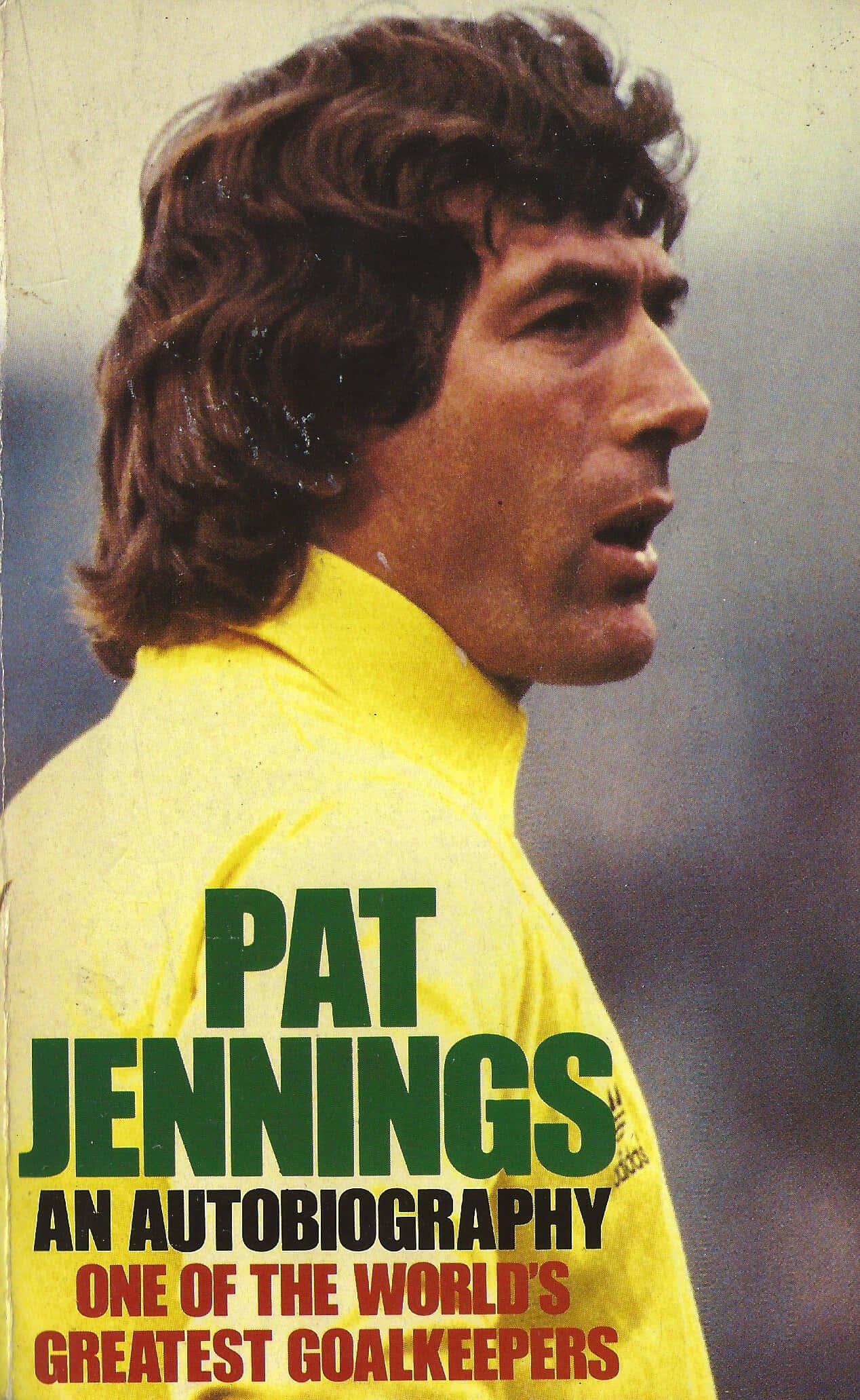 Pat Jennings 自傳書封面 壁紙 — 帕特·詹寧斯身穿黃色球衣的特寫，球衣上有粗體綠色和紅色文字宣告他的自傳。