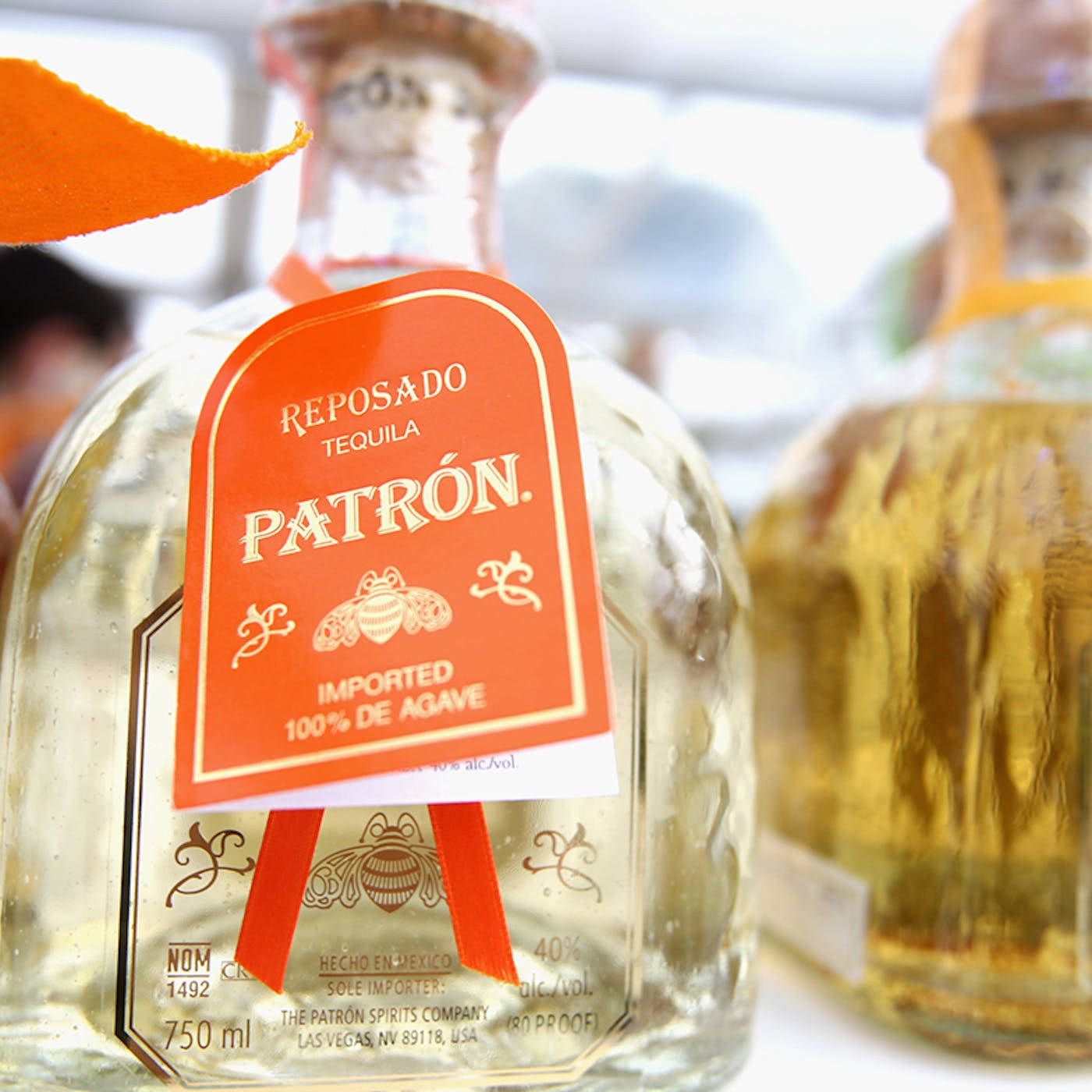 Patrón Reposado 龍舌蘭酒瓶的特寫，帶有橙色標籤和蜜蜂設計。