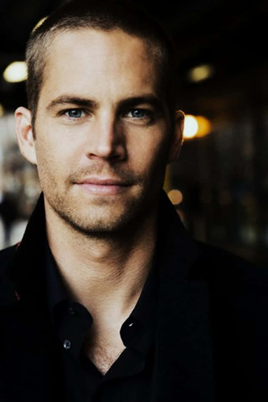 保羅·獲加 桌布 壁紙 — Paul Walker 身穿黑色襯衫，背景帶有柔和散景燈光的特寫肖像。