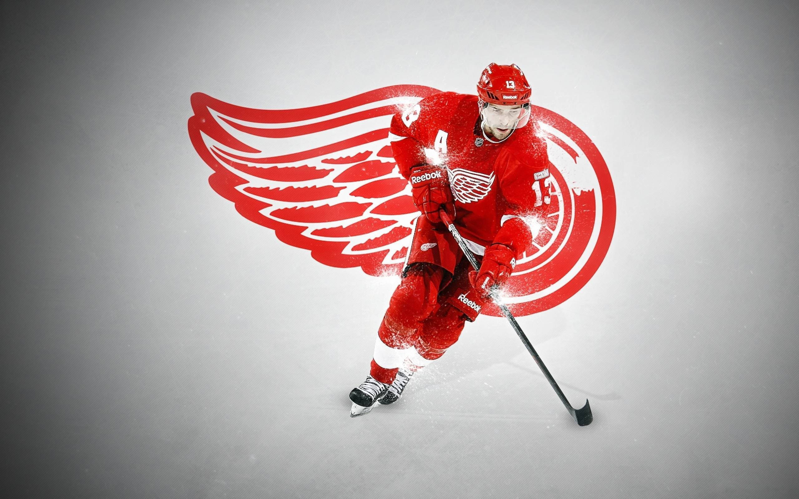 底特律紅翼隊球員 Pavel Datsyuk 壁紙 — 一名穿著紅色裝備的冰球運動員在灰色冰場上動態滑行，身後有發光的翅膀標誌。