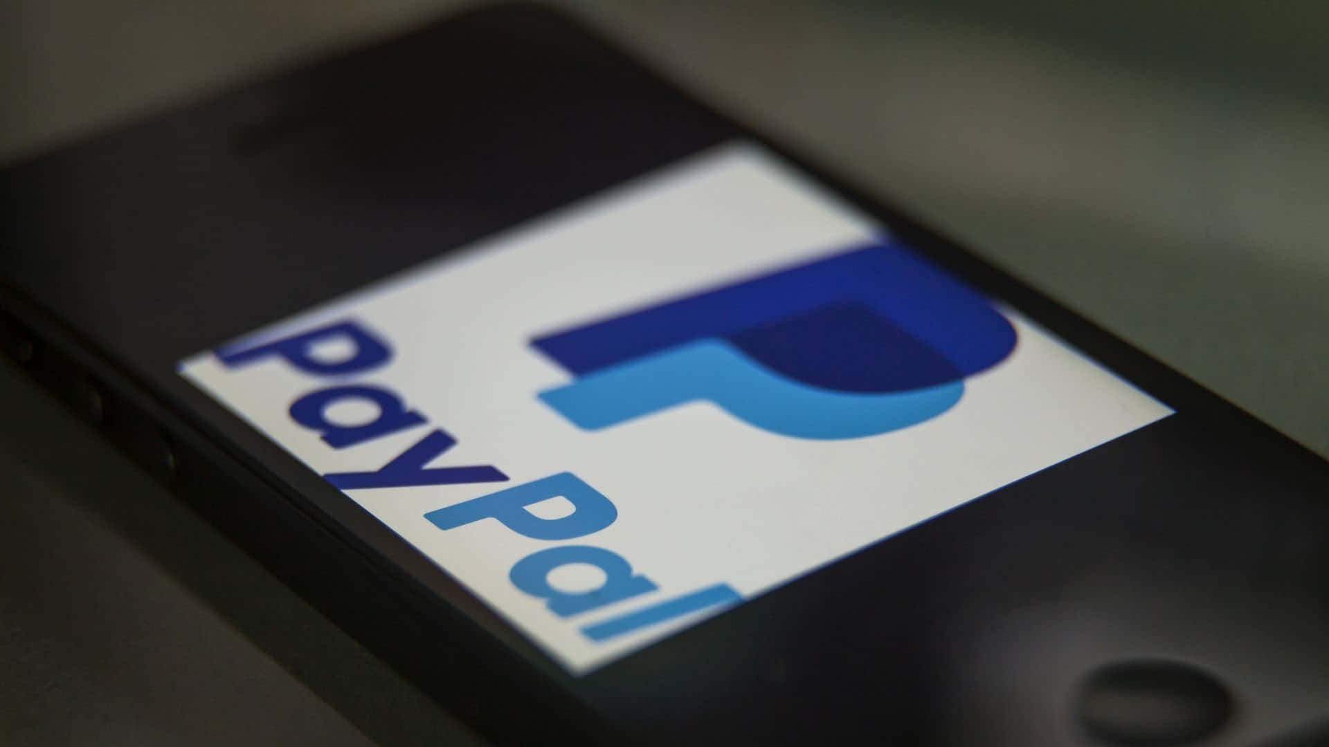 業界領先的安全保障，讓 PayPal 付款更安心 壁紙 — 智能手機屏幕特寫，顯示藍色和白色的PayPal標誌，背景模糊深色。