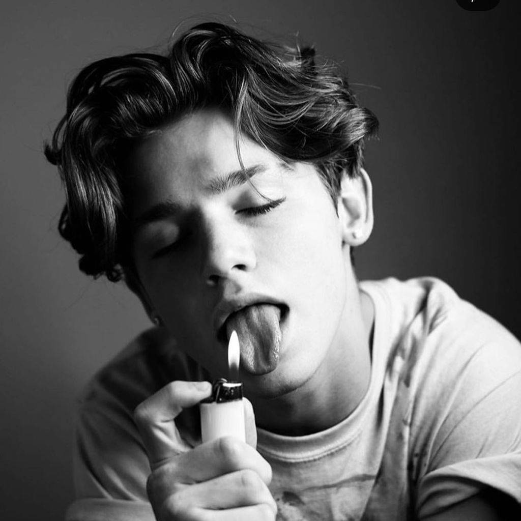 Payton Moormeier 黑白影像 壁紙 — 一個黑白肖像，一個頭髮蓬鬆的年輕男子拿著點燃的打火機放在舌頭上。