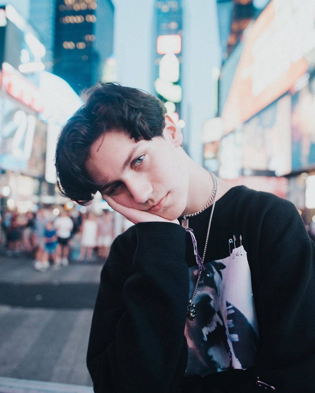 Payton Moormeier 在城市中 壁紙 — 一個年輕人在夜晚霓虹燈閃爍的繁忙街道上，將頭靠在手上。