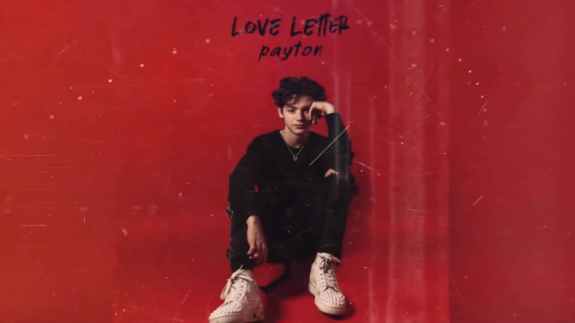 Payton Moormeier 愛情信箋 壁紙 — 一位身穿黑色服裝和白色運動鞋的年輕男子靠著帶有紋理的紅色牆壁坐著，上方有「LOVE LETTER payton」文字。