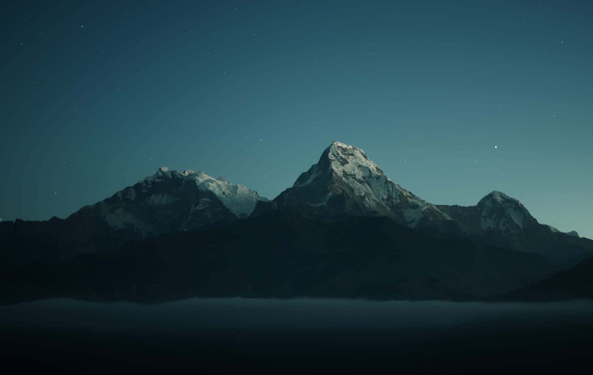 積雪的山峰在星空下的霧氣之上聳立。