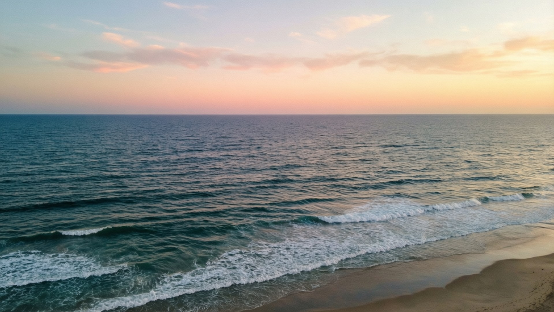 海浪在粉紅橙色日落天空下衝擊沙灘